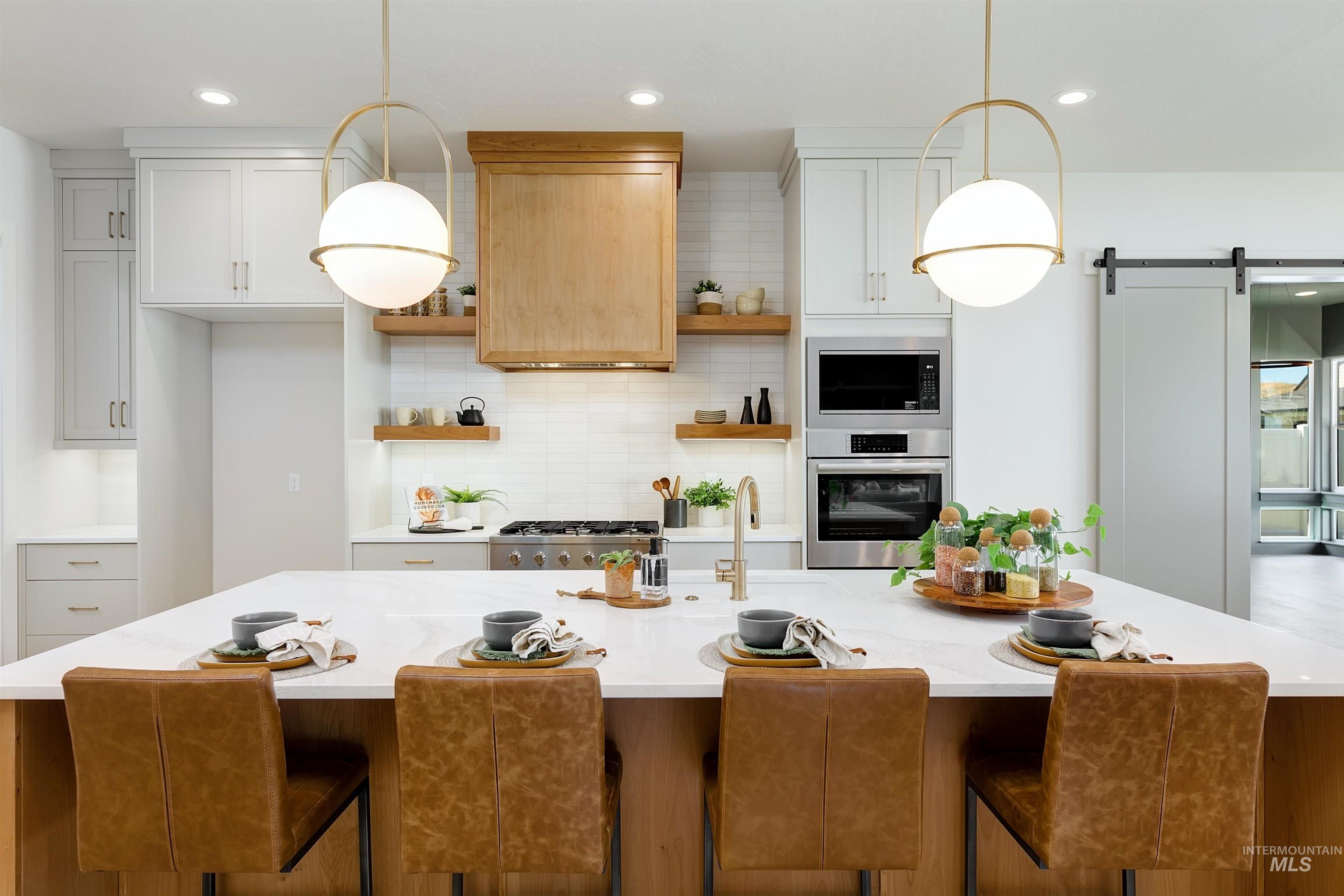 Kitchen with stainless steel appliances, open shelves, light countertops, a kitchen island with sink, and recessed lighting
