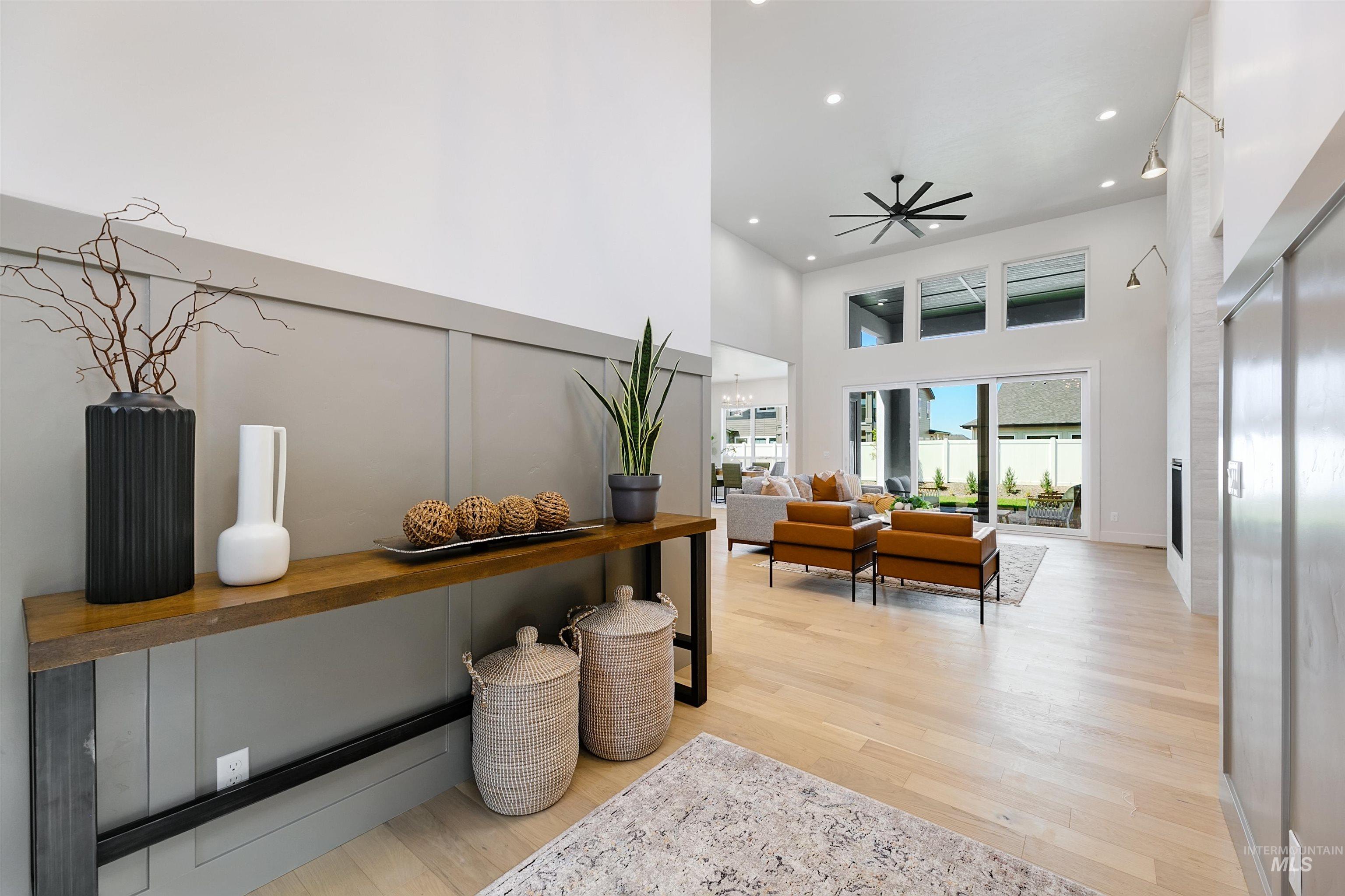 Hallway with a high ceiling, wood finished floors, and recessed lighting