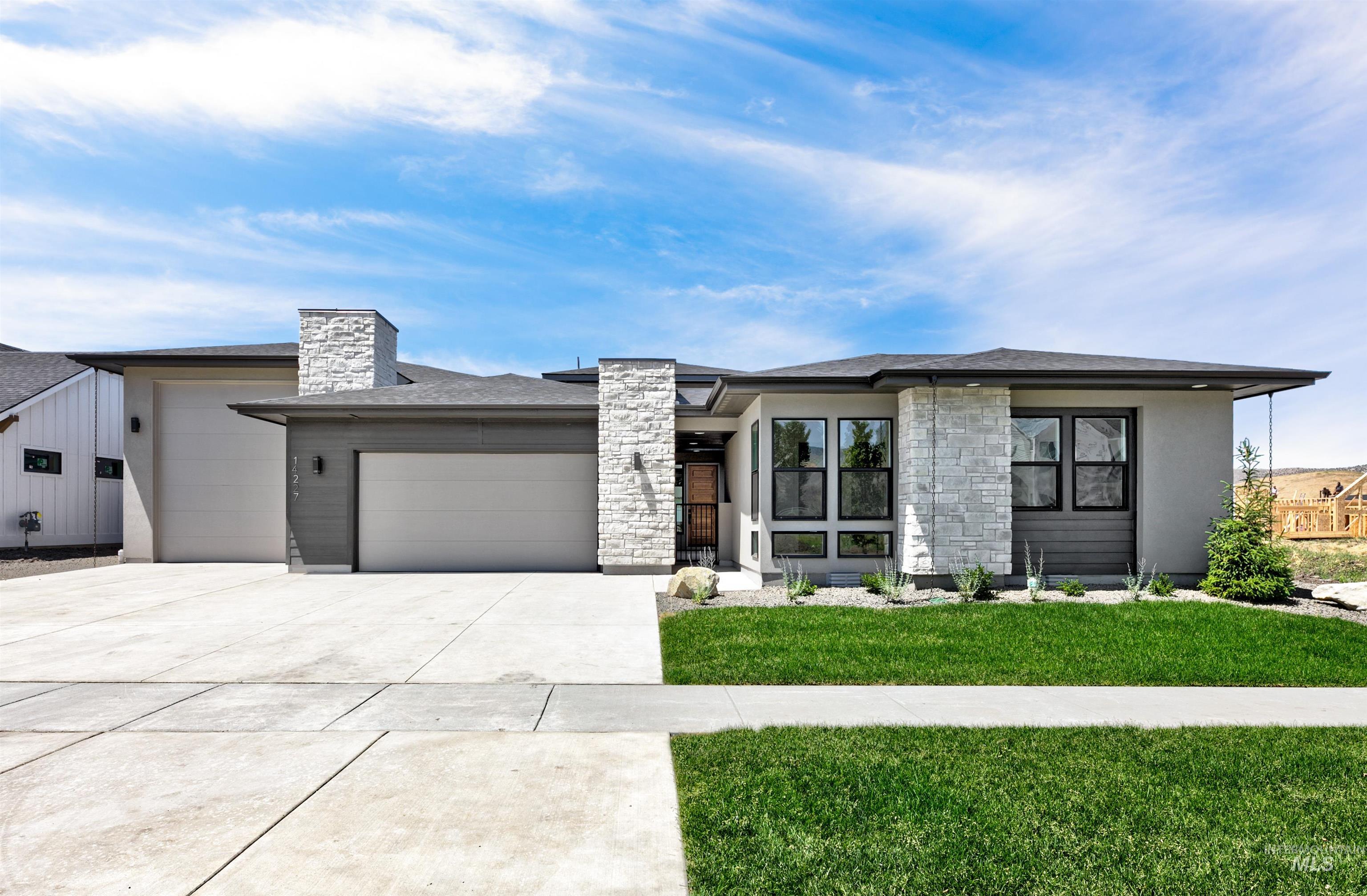View of front facade with a garage, driveway, stone siding, a front lawn, and stucco siding