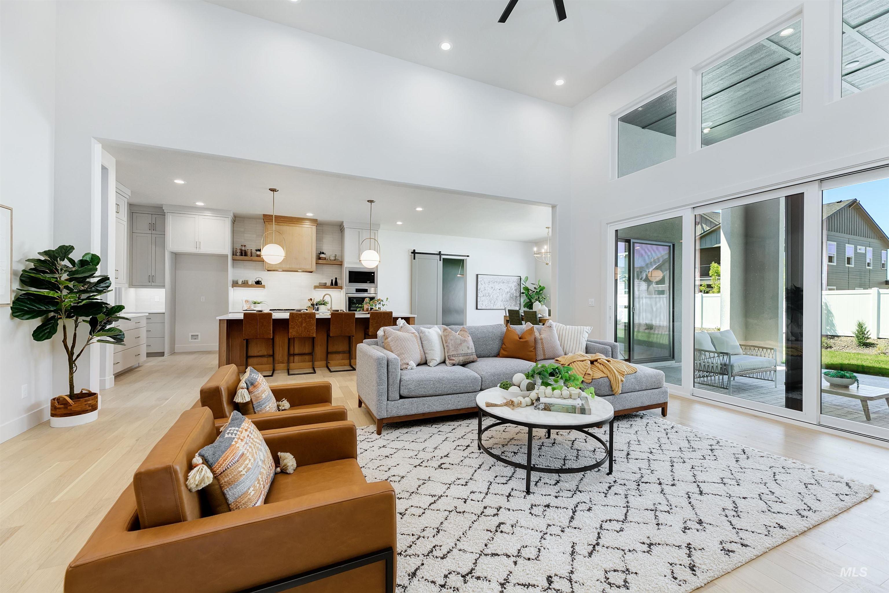 Living area with a towering ceiling, healthy amount of natural light, light wood-style floors, a barn door, and recessed lighting