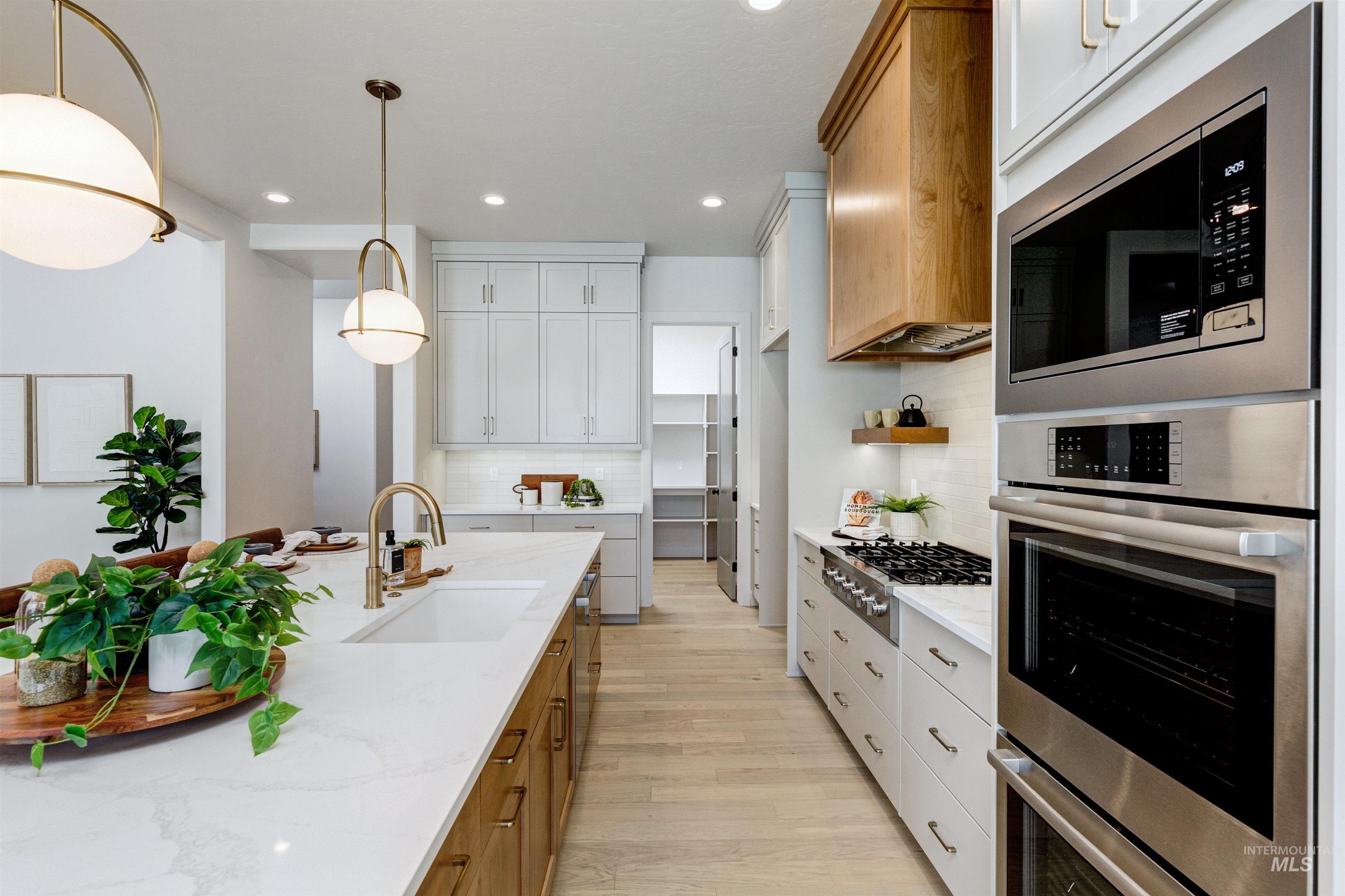 Kitchen featuring stainless steel appliances, light wood-style flooring, decorative backsplash, recessed lighting, and light stone countertops