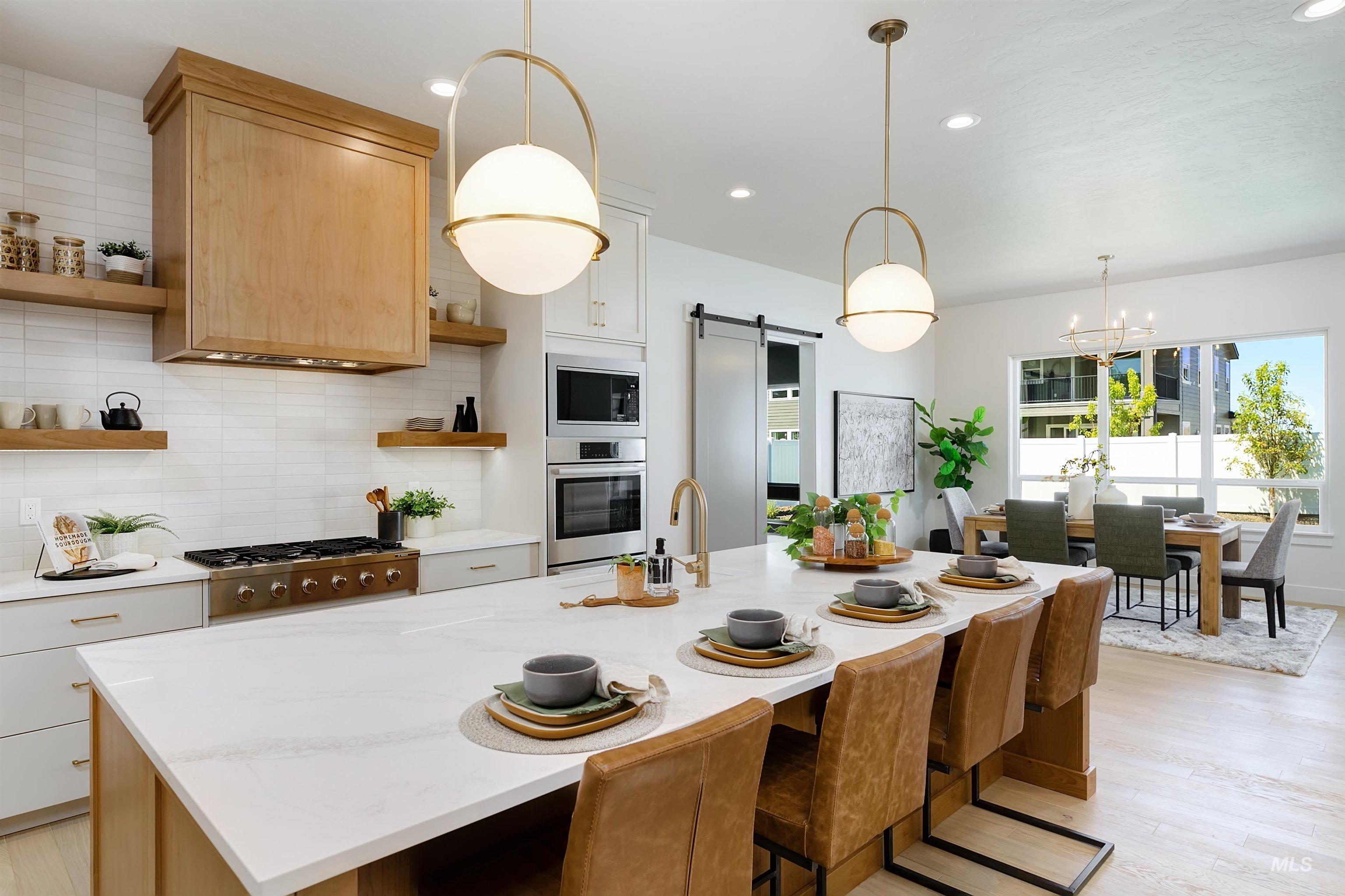 Kitchen with open shelves, appliances with stainless steel finishes, a barn door, tasteful backsplash, and recessed lighting