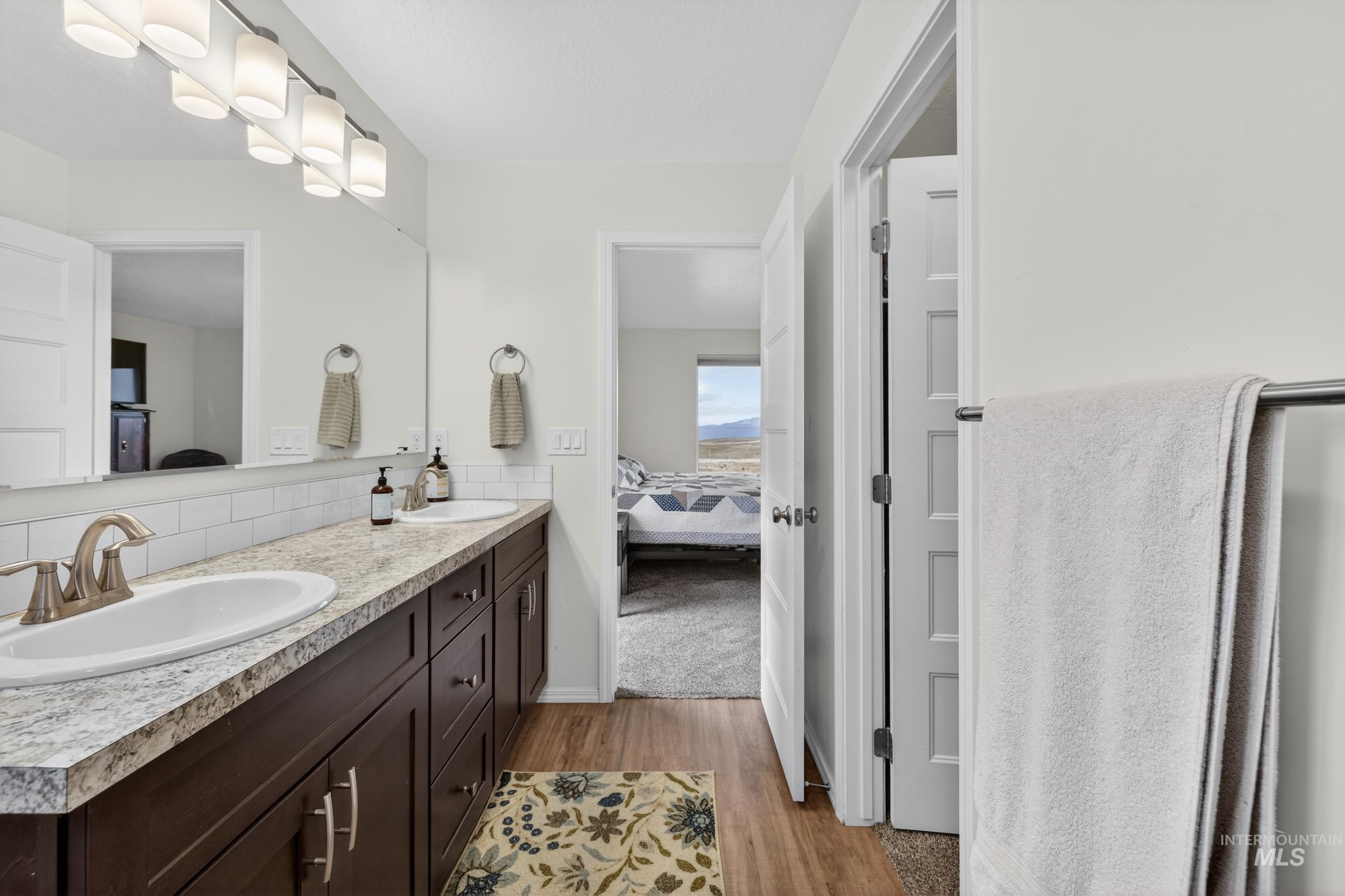 Full bathroom featuring ensuite bathroom, double vanity, and light wood finished floors