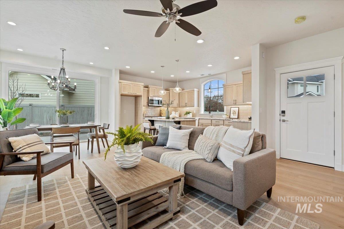 Living area with light wood-style flooring, a chandelier, a ceiling fan, and recessed lighting