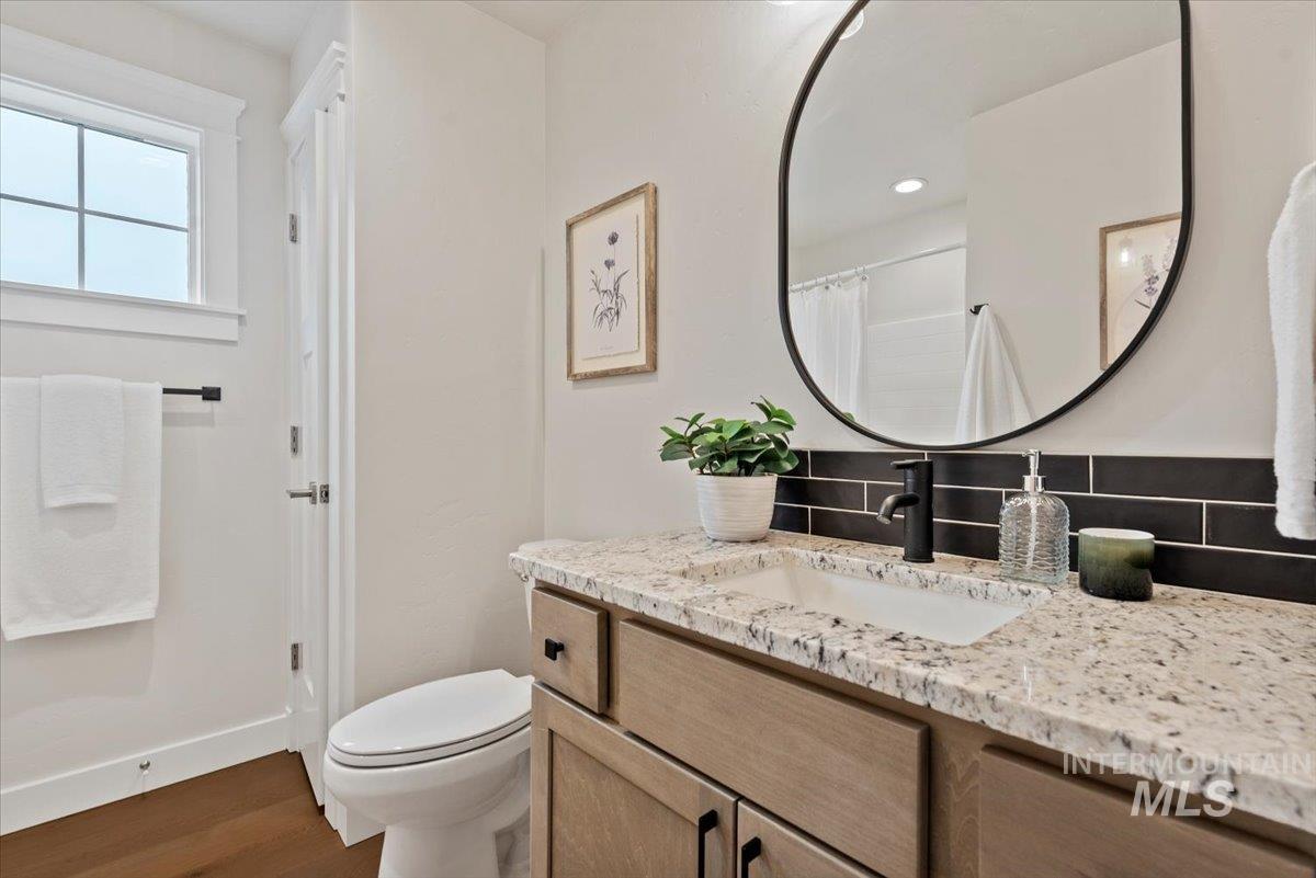 Full bathroom featuring vanity, tasteful backsplash, curtained shower, and dark wood-style floors