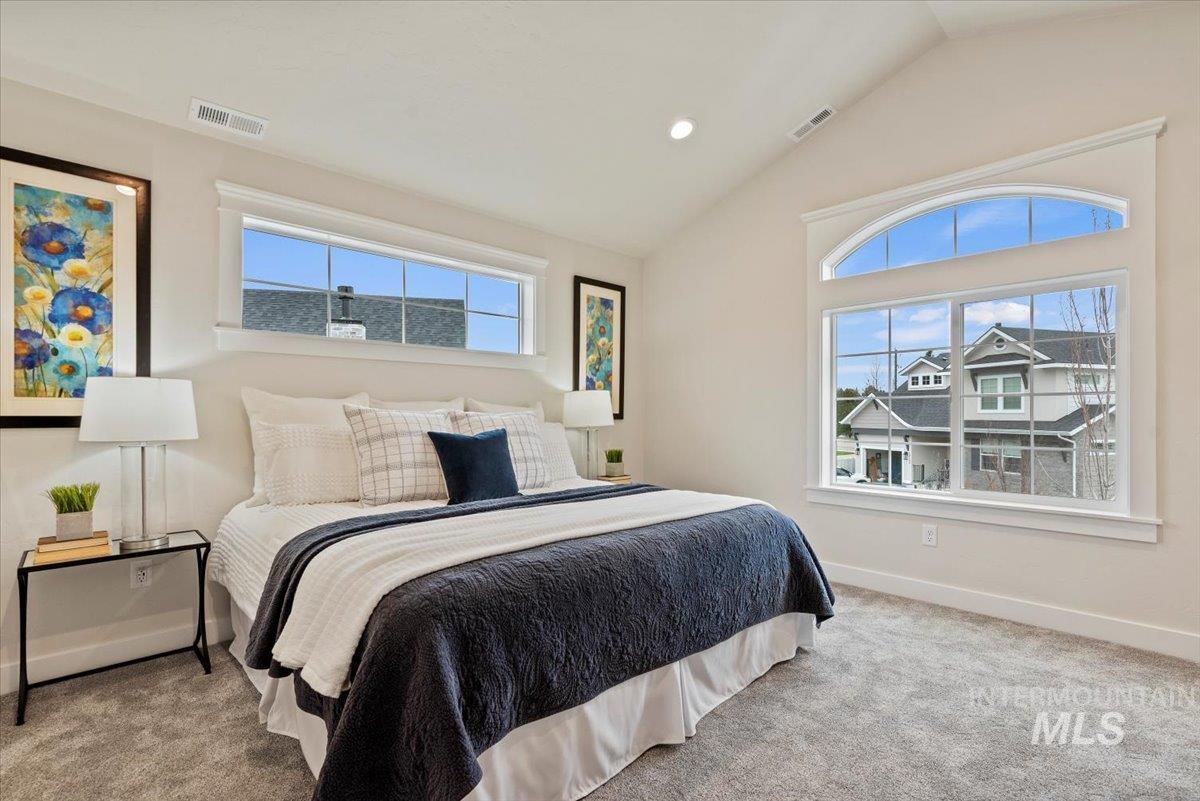 Carpeted bedroom featuring vaulted ceiling, multiple windows, and recessed lighting