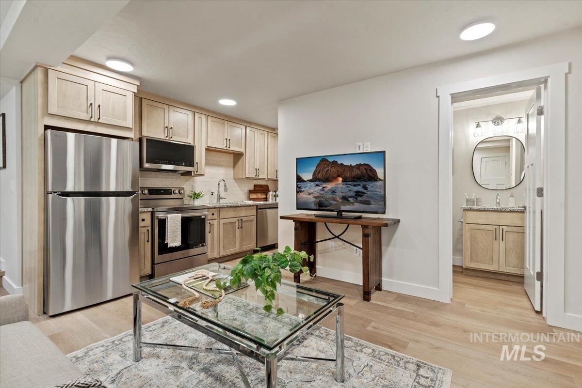 Kitchen featuring appliances with stainless steel finishes, light brown cabinets, light wood-type flooring, recessed lighting, and decorative backsplash