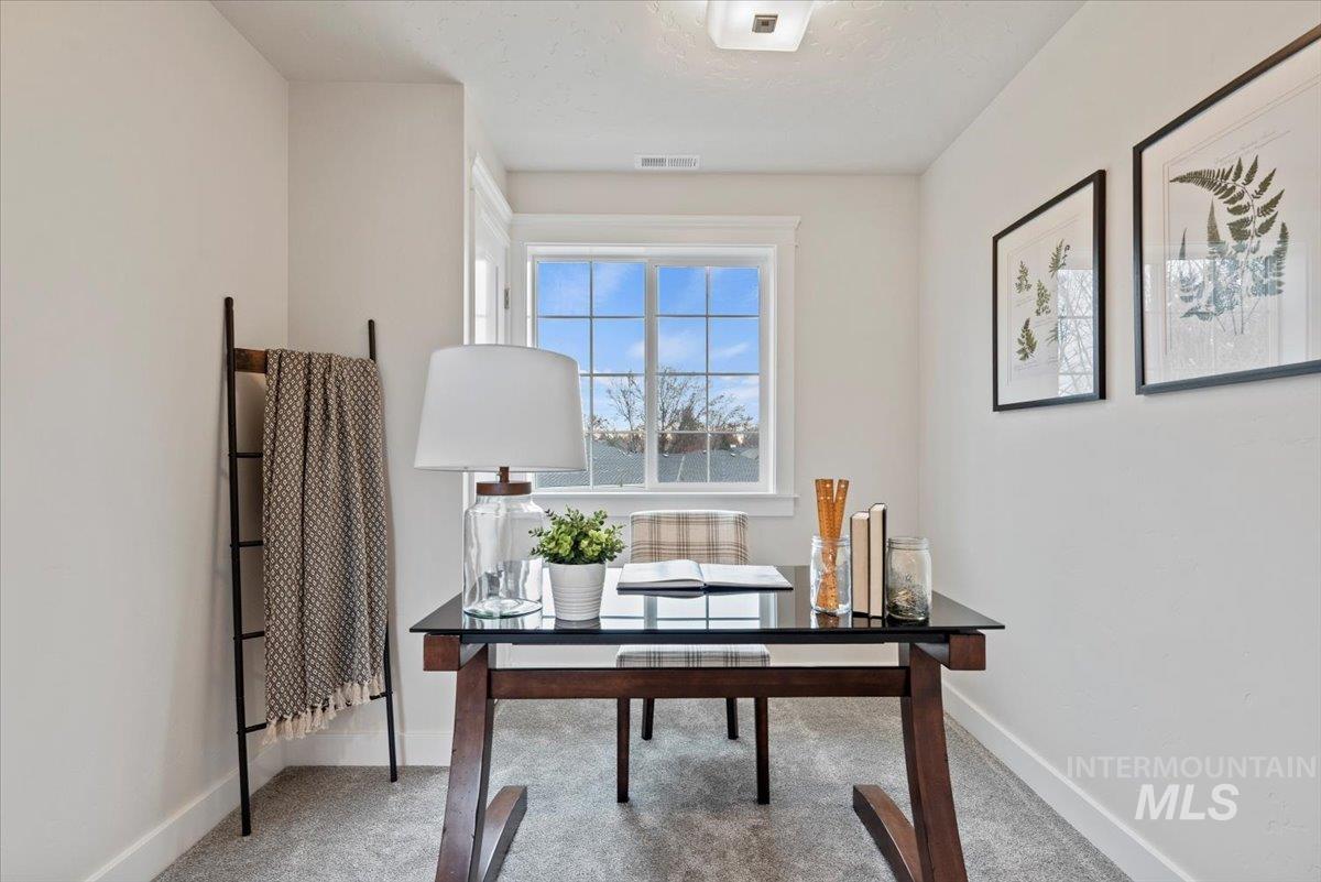 Office area featuring light carpet and a textured ceiling
