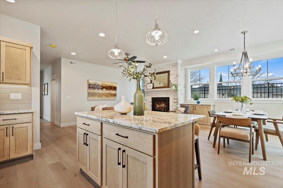 Kitchen featuring light brown cabinetry, light stone countertops, a kitchen island, light wood-style flooring, and recessed lighting
