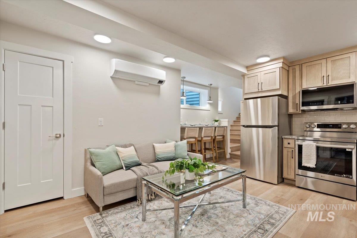 Living area featuring light wood-type flooring, a wall mounted AC, and recessed lighting