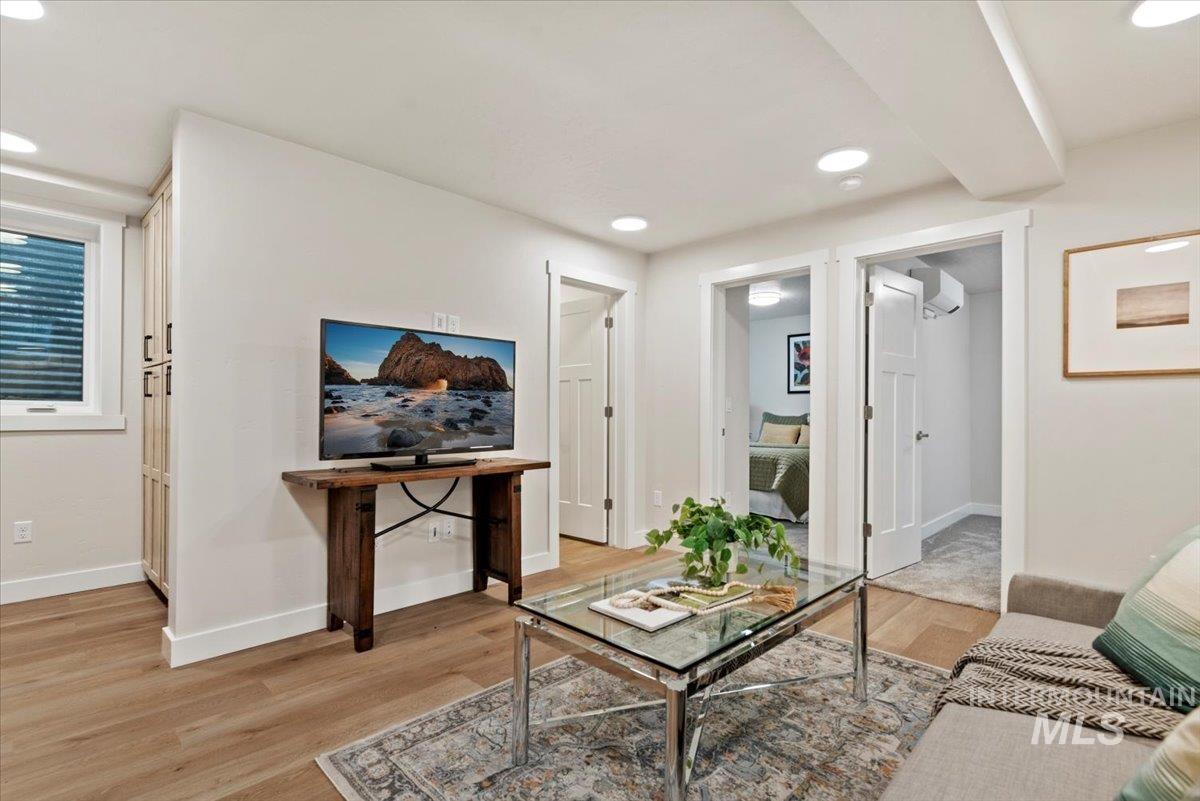 Living area with light wood finished floors, recessed lighting, and a wall mounted AC