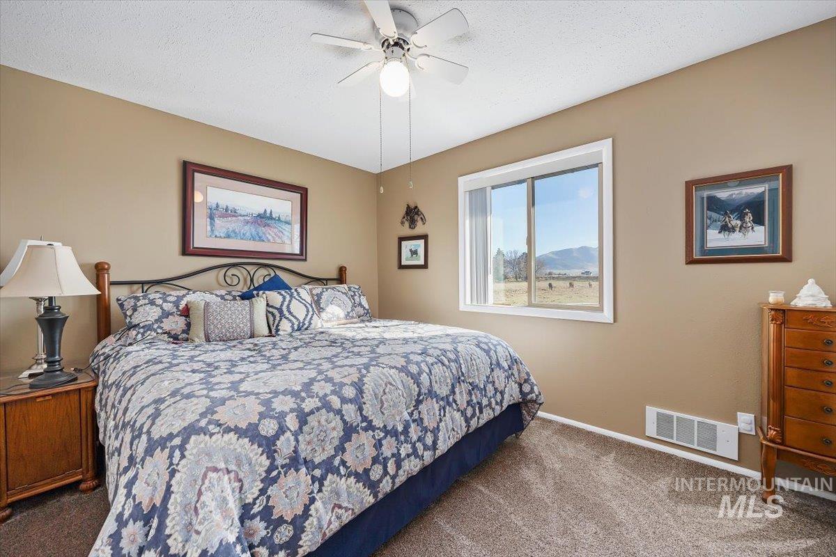 Bedroom featuring carpet floors, a textured ceiling, and a ceiling fan