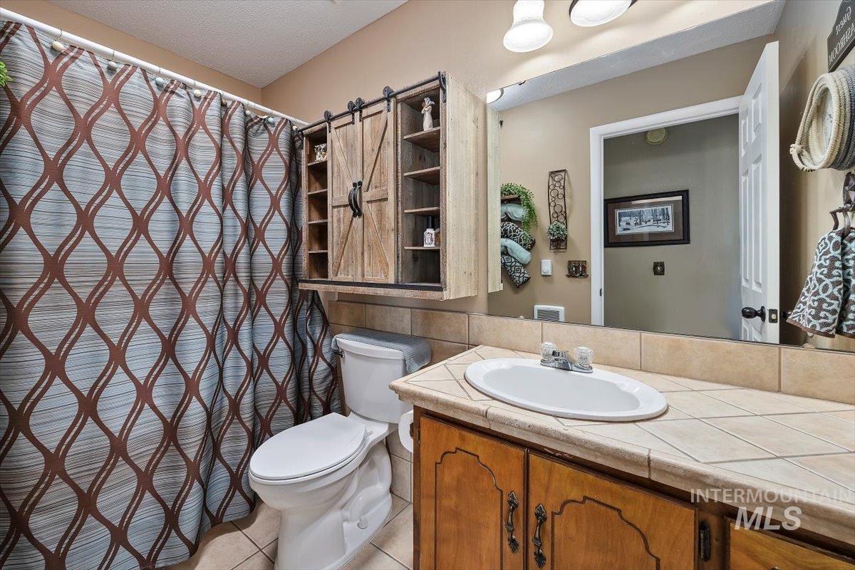 Full bath featuring a shower with shower curtain, light tile patterned floors, vanity, and a textured ceiling