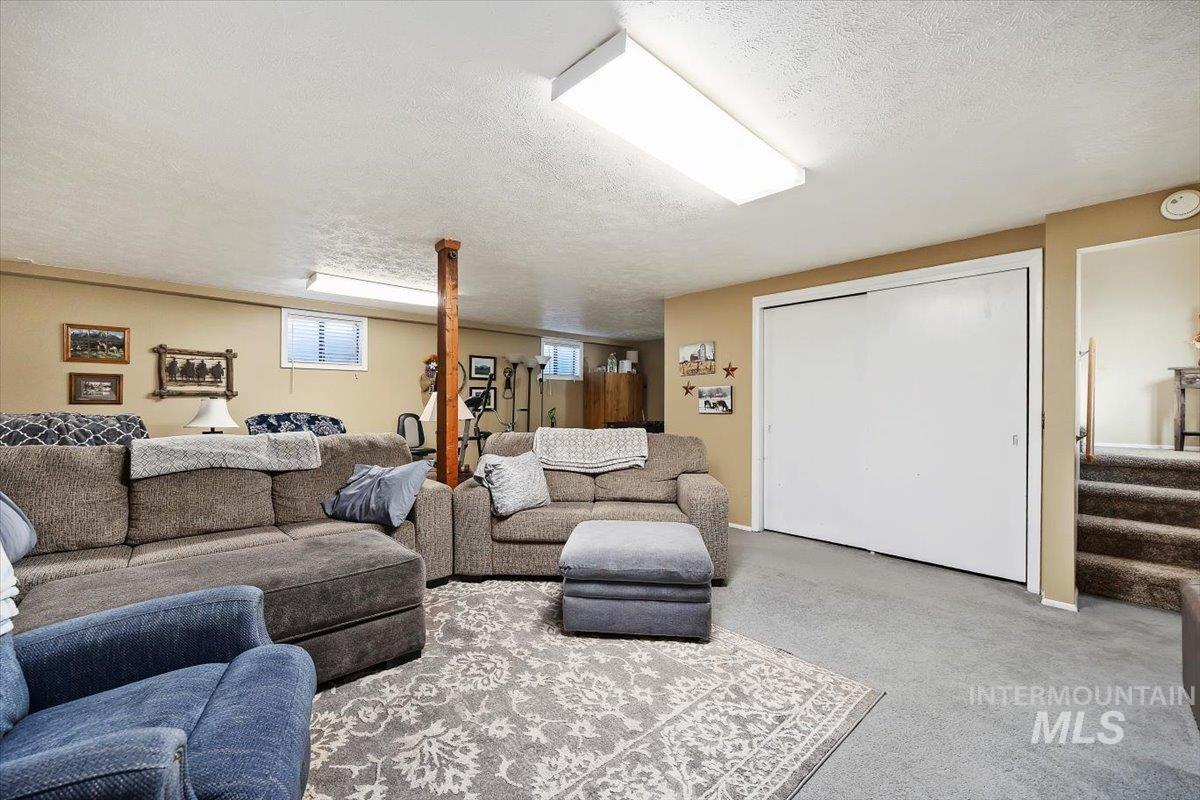 Living area with a textured ceiling, carpet flooring, and stairway