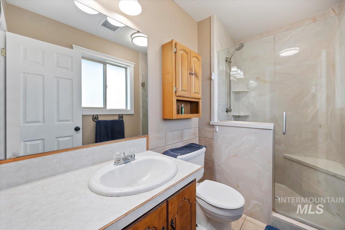 Bathroom featuring vanity, a marble finish shower, and tile walls