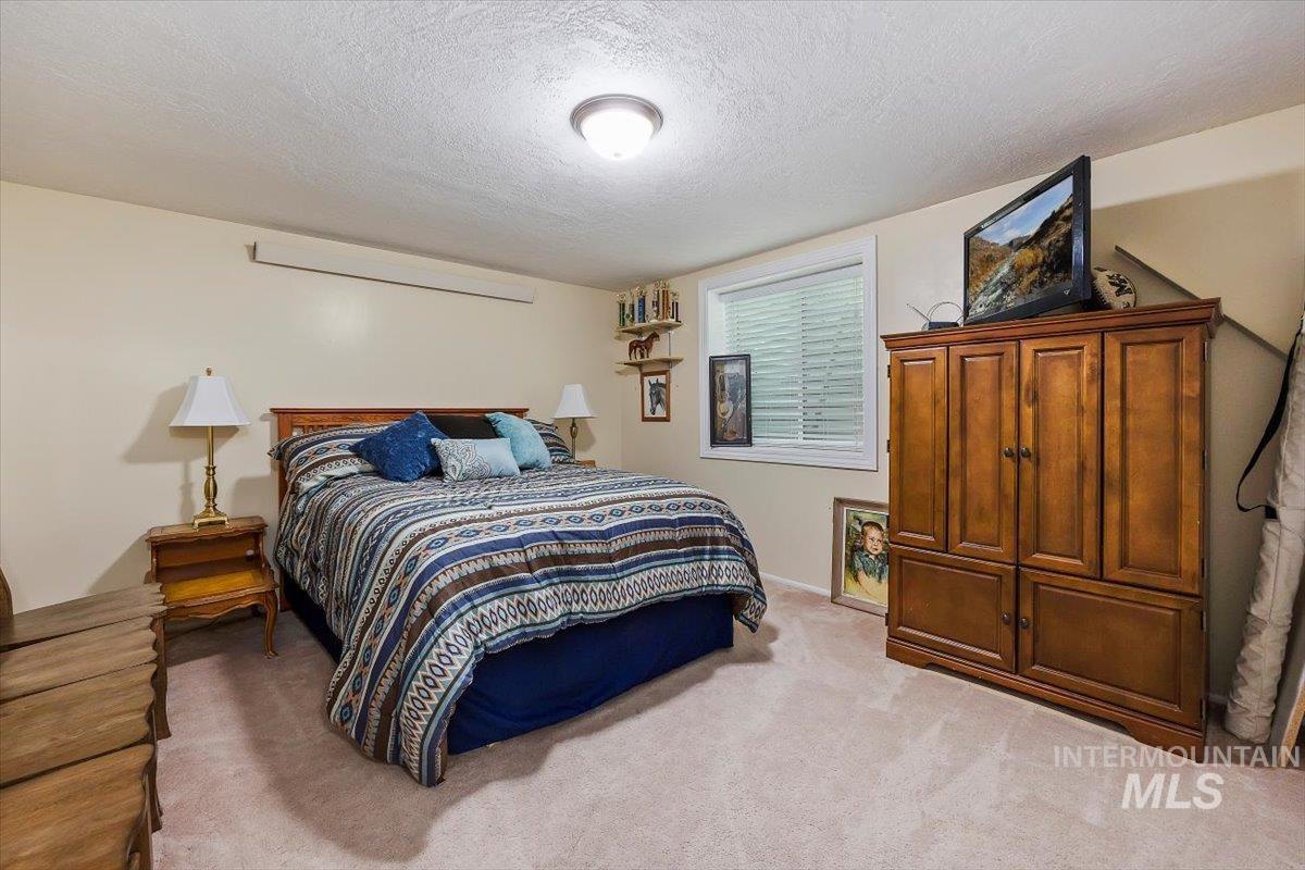 Bedroom with a textured ceiling and light carpet