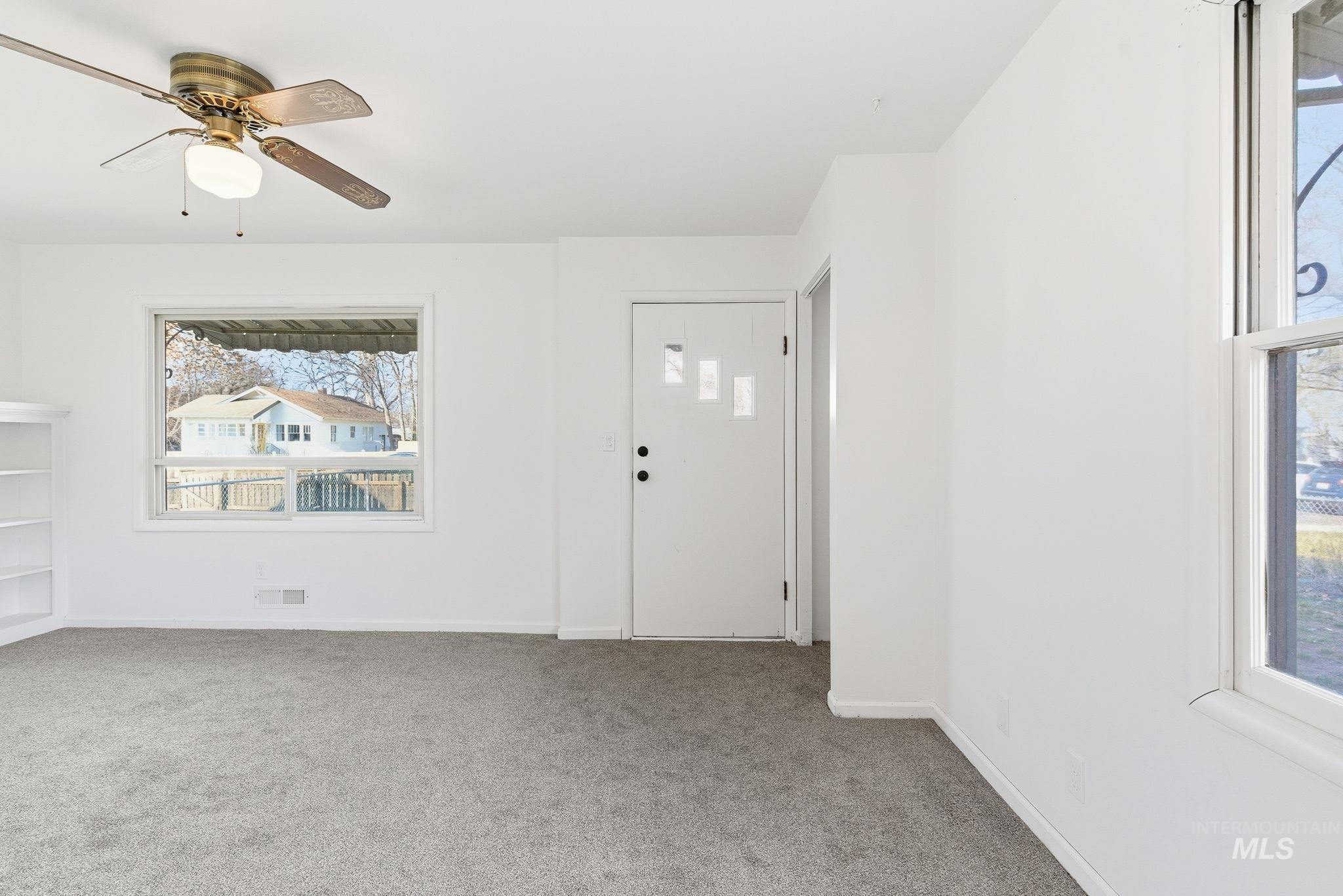 Entrance foyer featuring healthy amount of natural light, light carpet, and a ceiling fan