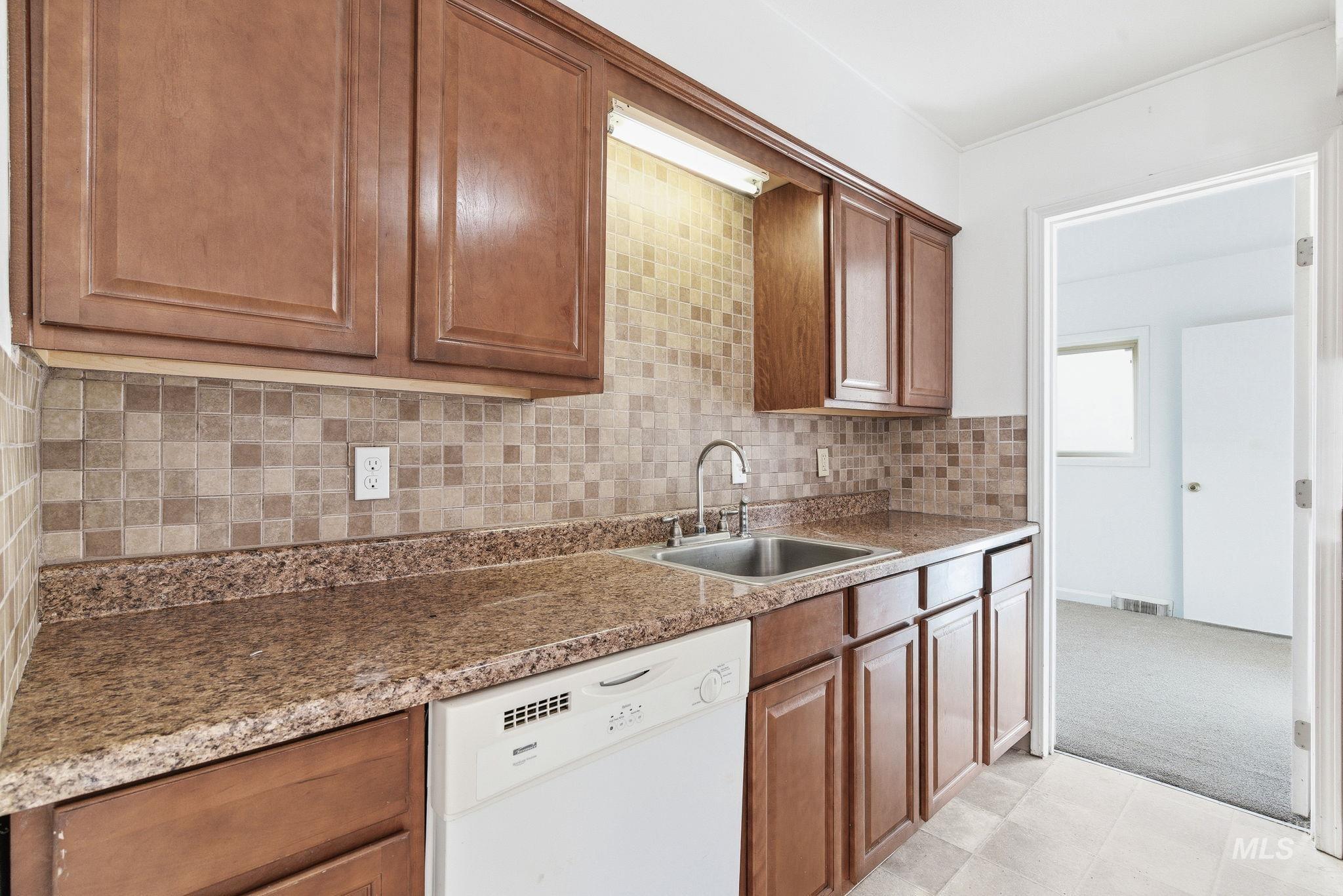 Kitchen featuring dishwasher, brown cabinets, and decorative backsplash