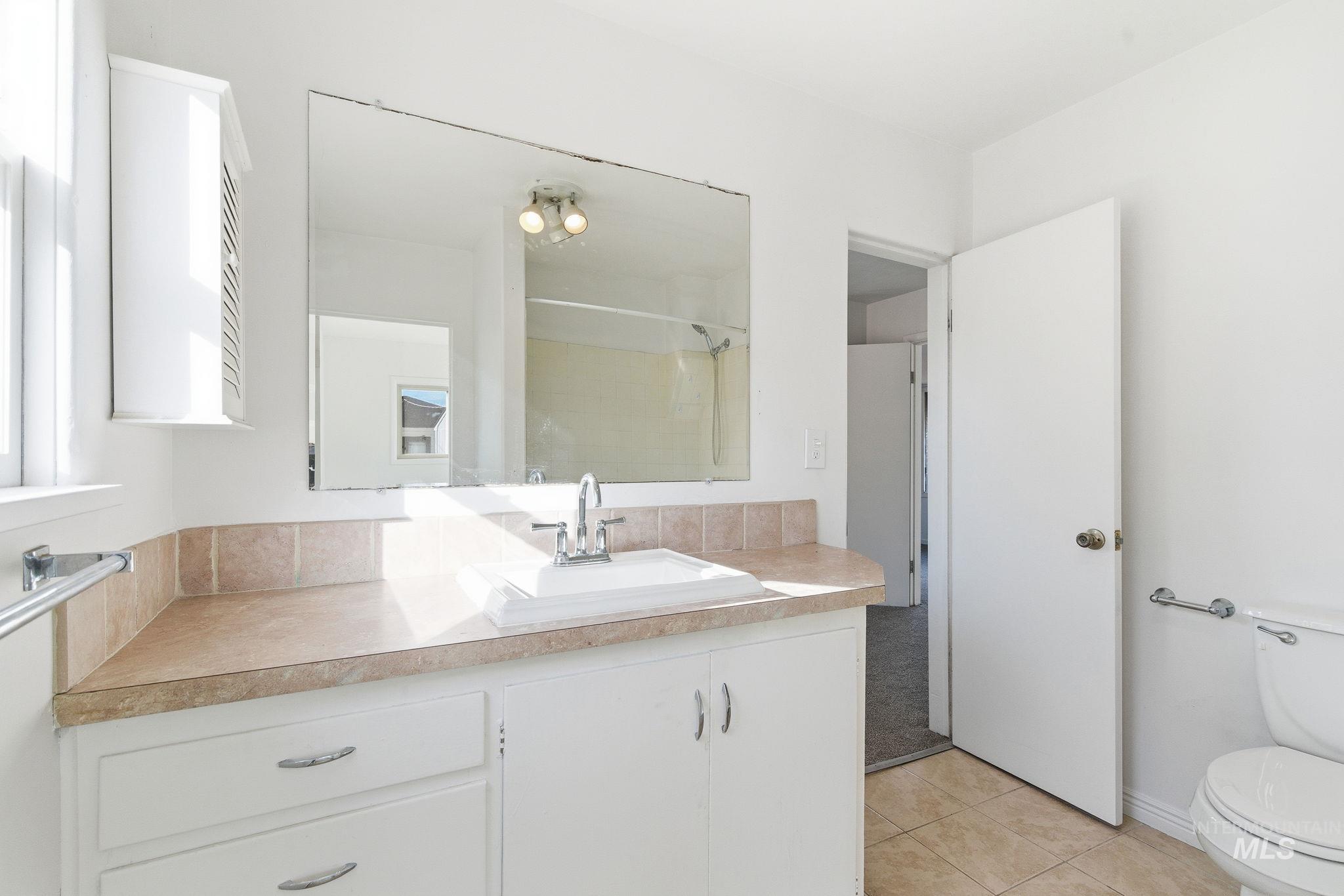 Bathroom featuring vanity, light tile patterned floors, and a shower