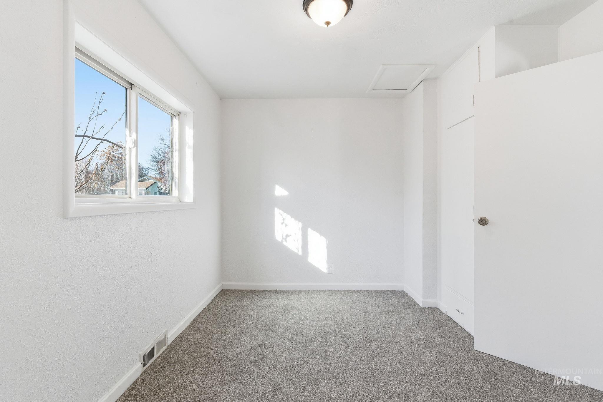 Carpeted spare room with attic access and baseboards