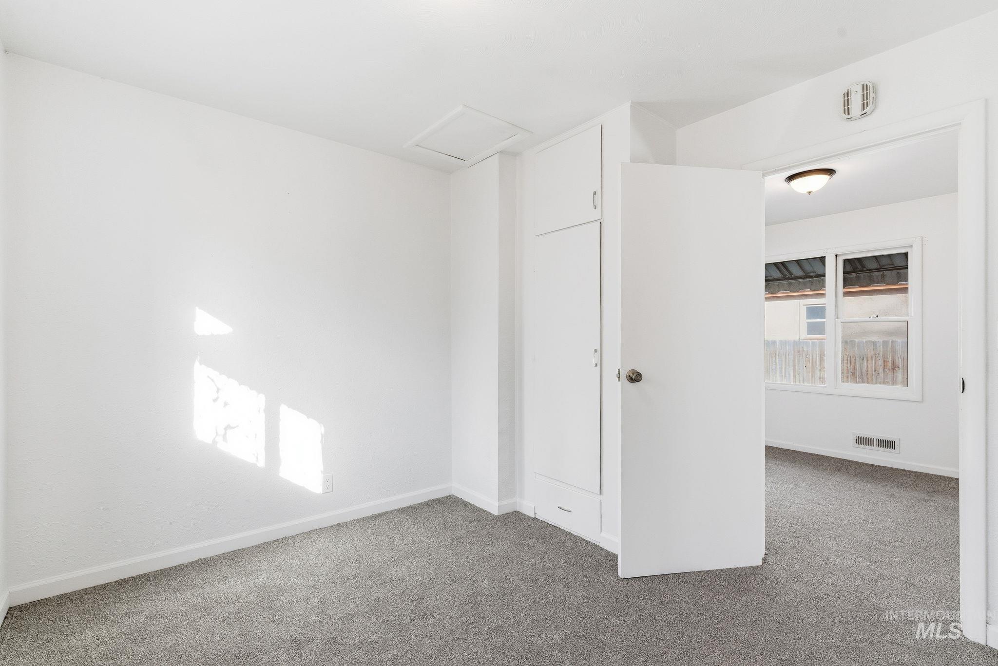 Unfurnished room with attic access and carpet