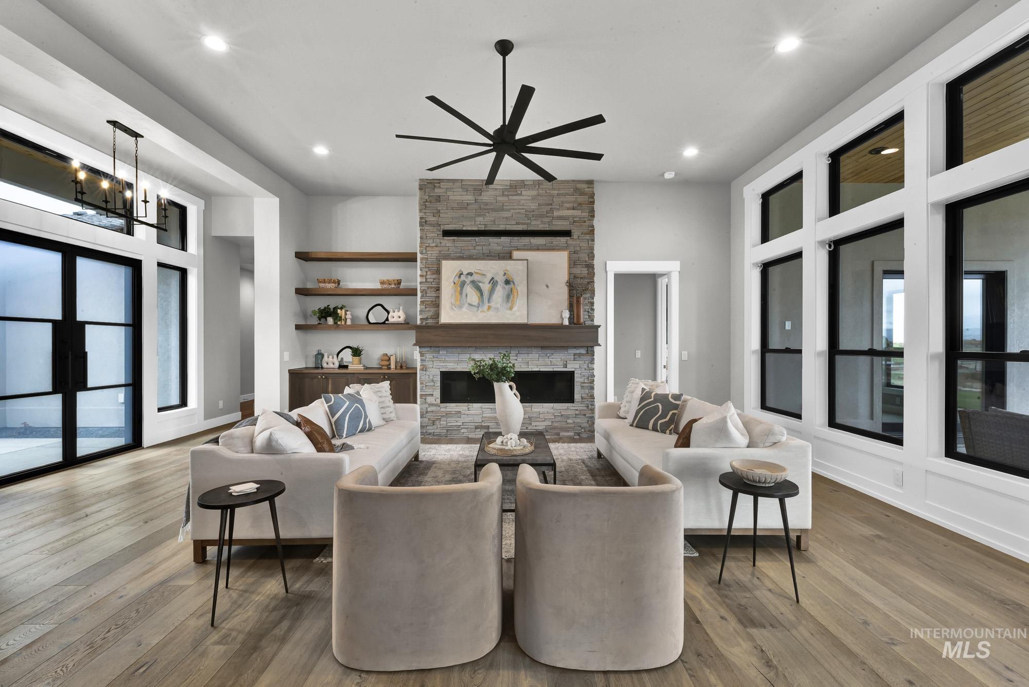 Living room with healthy amount of natural light, wood finished floors, recessed lighting, a fireplace, and a high ceiling