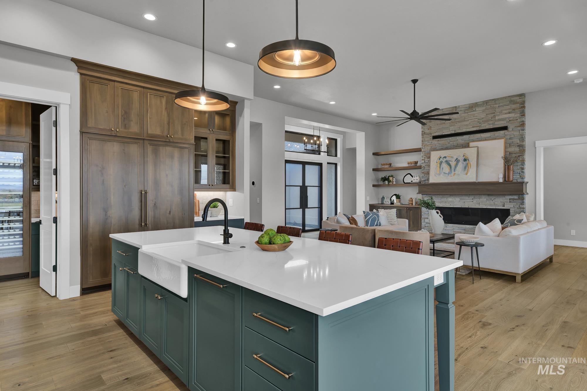 Kitchen featuring a kitchen island with sink, hanging light fixtures, light wood-type flooring, a fireplace, and recessed lighting
