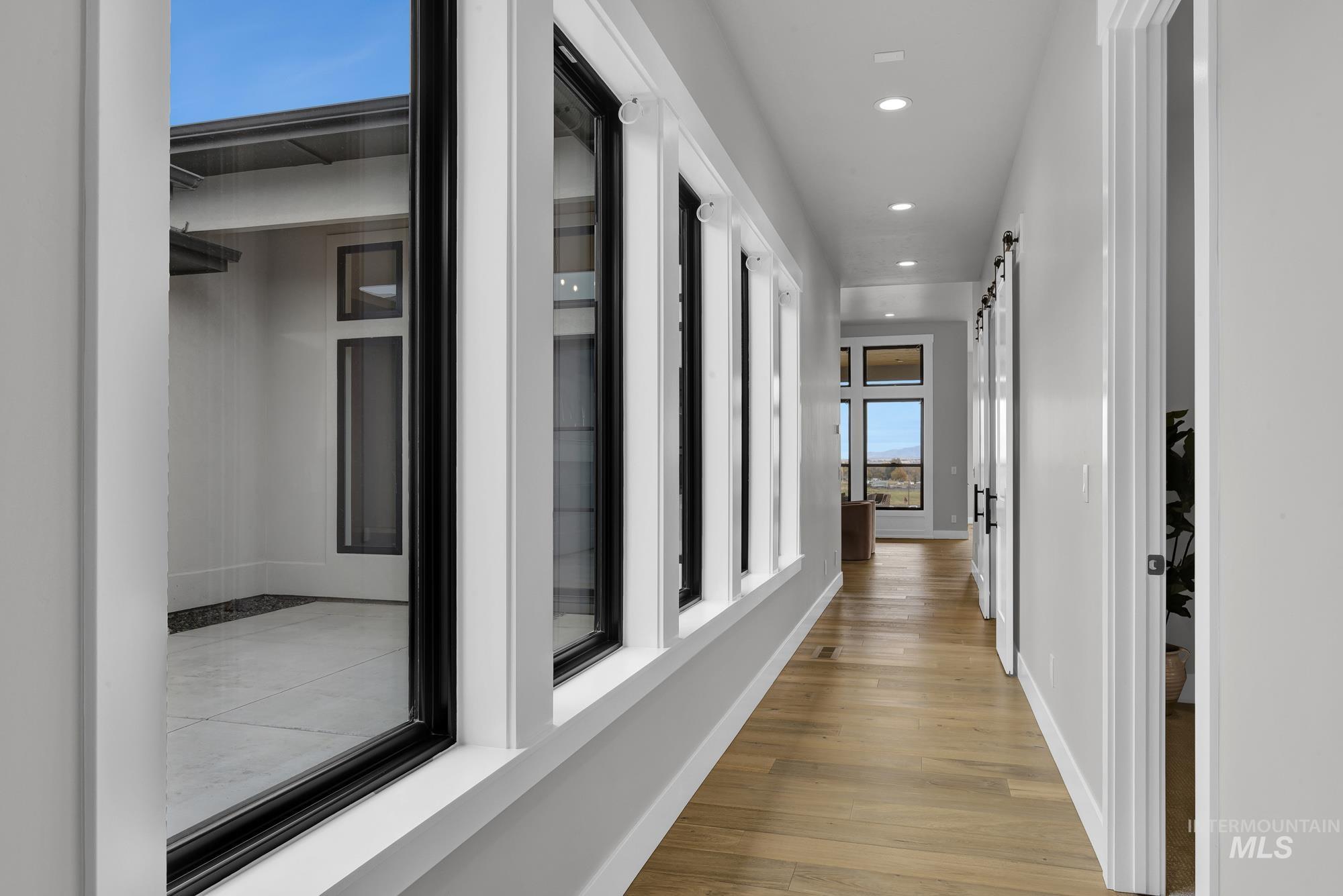 Corridor with a barn door, light wood-style flooring, and recessed lighting