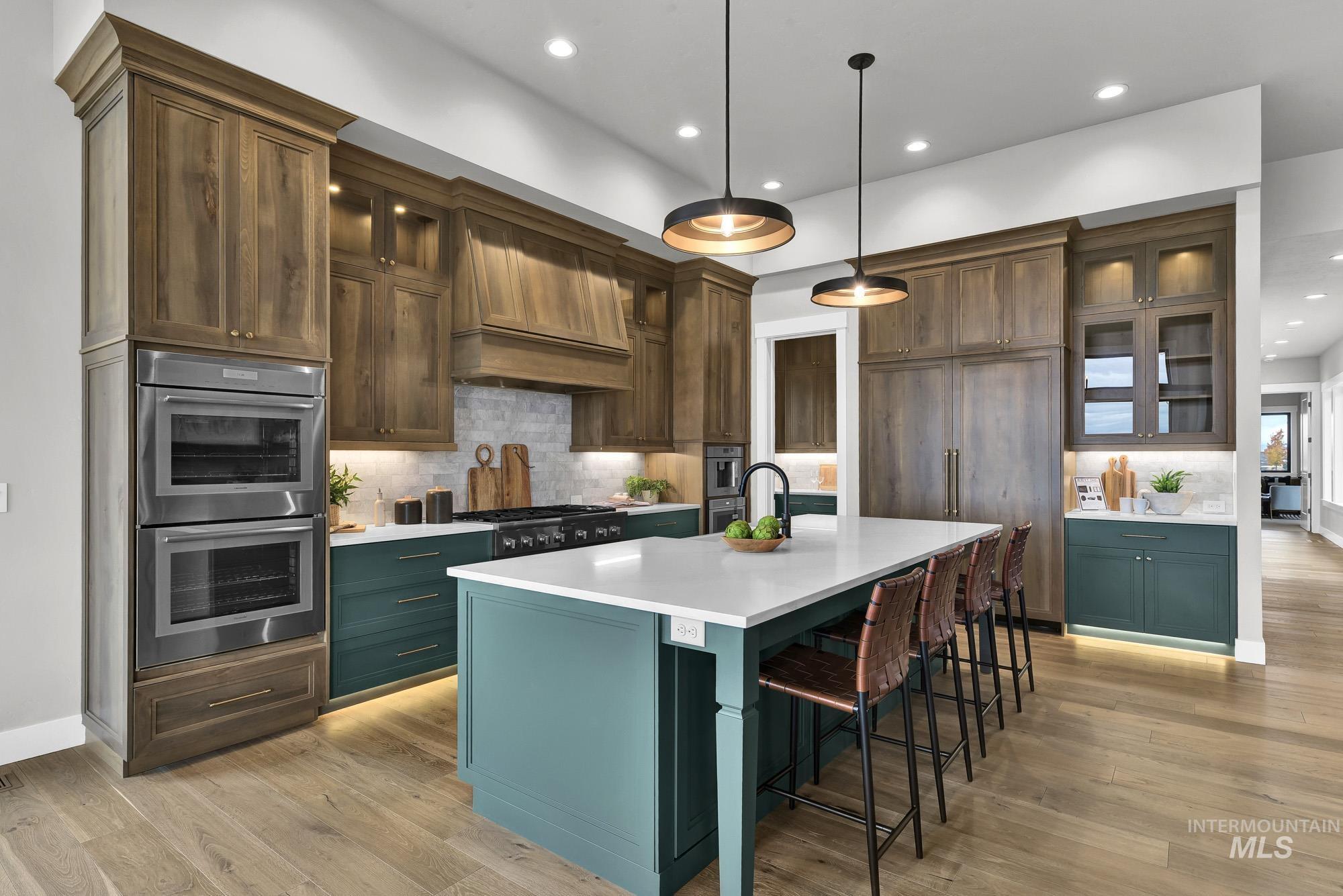 Kitchen with glass insert cabinets, decorative backsplash, recessed lighting, pendant lighting, and an island with sink