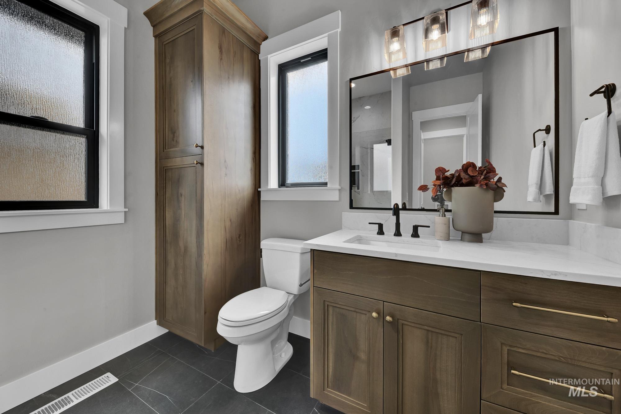 Bathroom featuring a shower, dark tile patterned flooring, and vanity