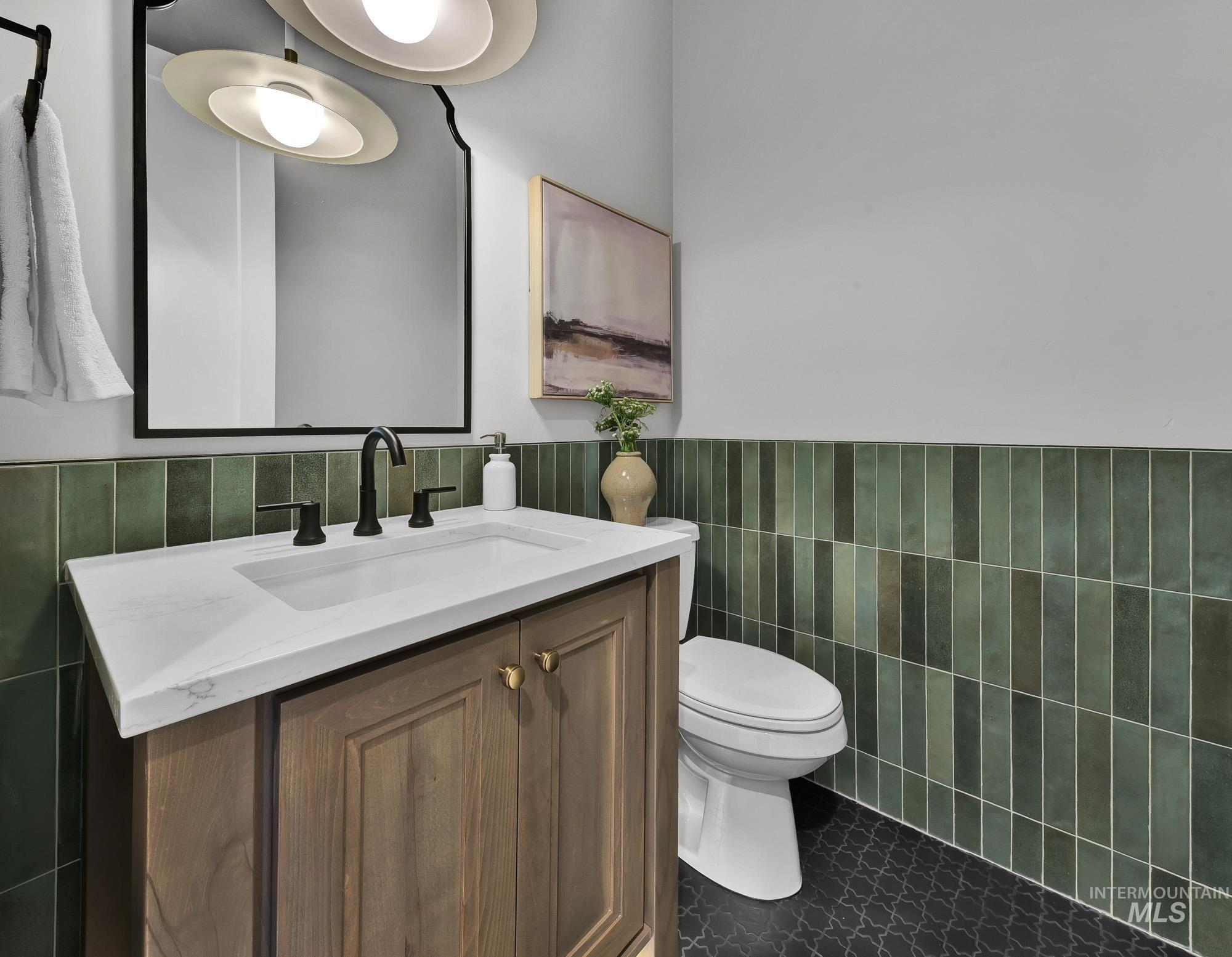 Half bath featuring tile walls, vanity, tile patterned floors, and wainscoting