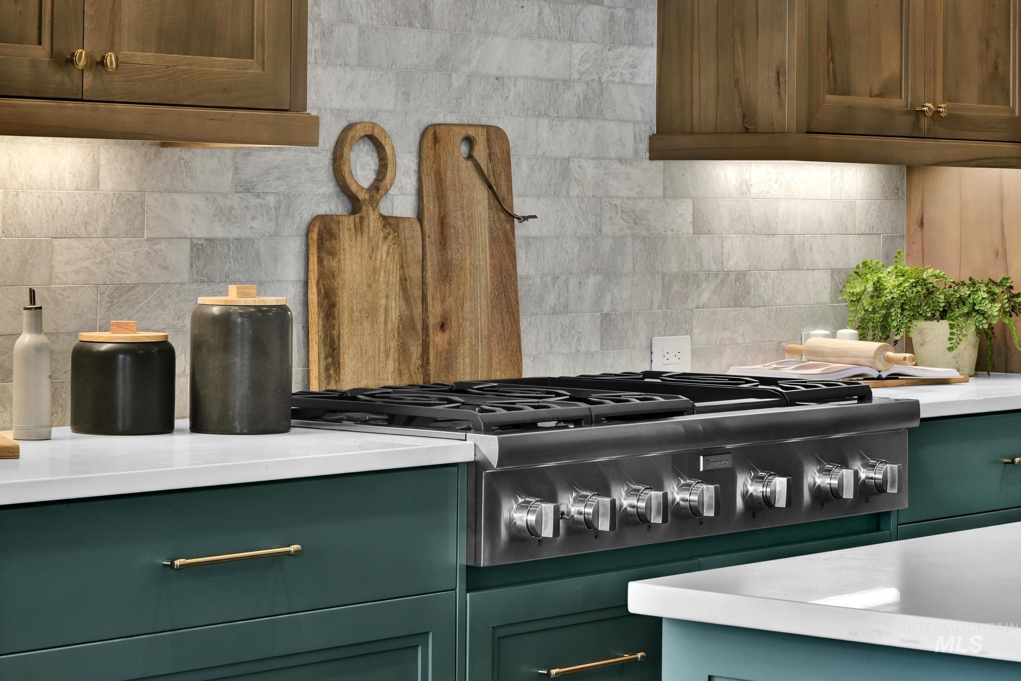 Kitchen with green cabinets, stainless steel gas stovetop, and backsplash