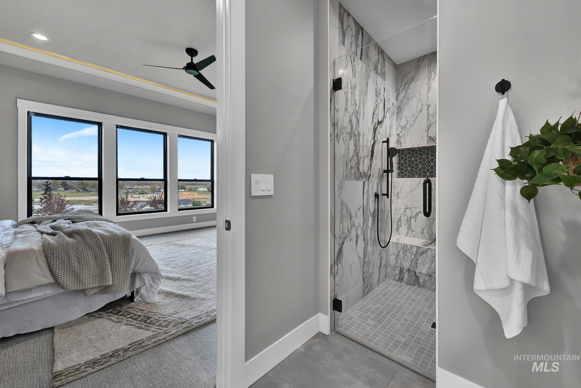 Bathroom with a marble finish shower, ceiling fan, and tile patterned flooring