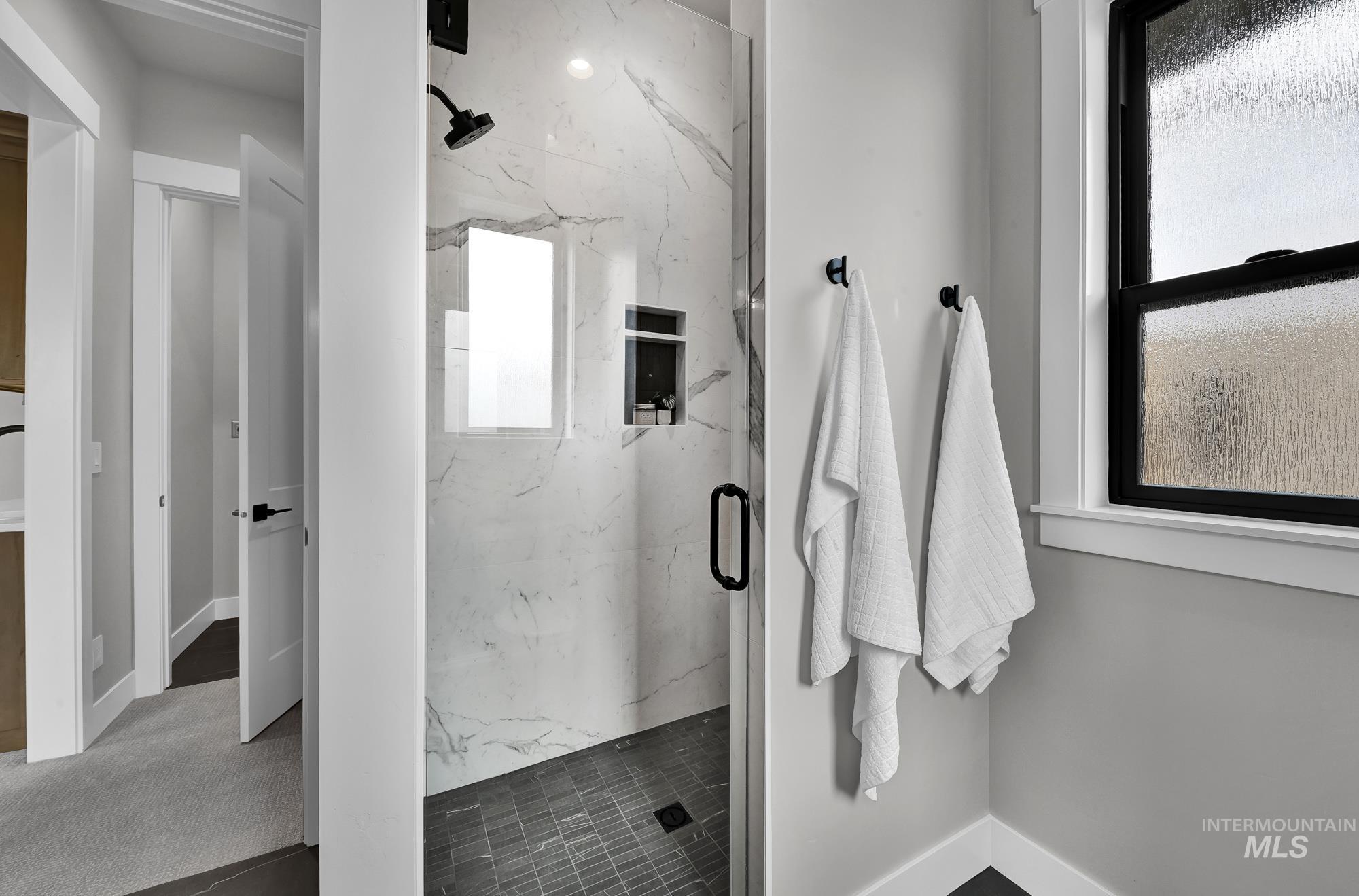 Bathroom featuring a marble finish shower and baseboards