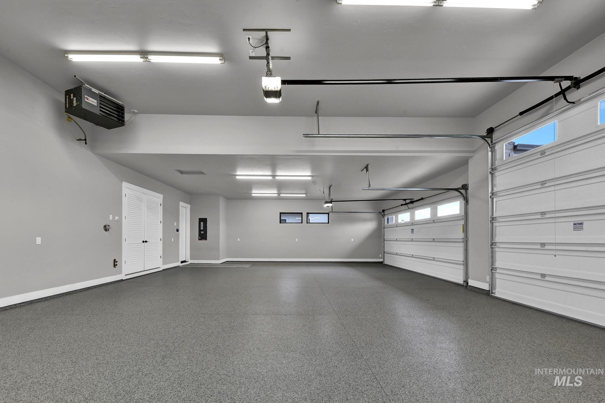 Garage featuring a heating unit, a garage door opener, and electric panel