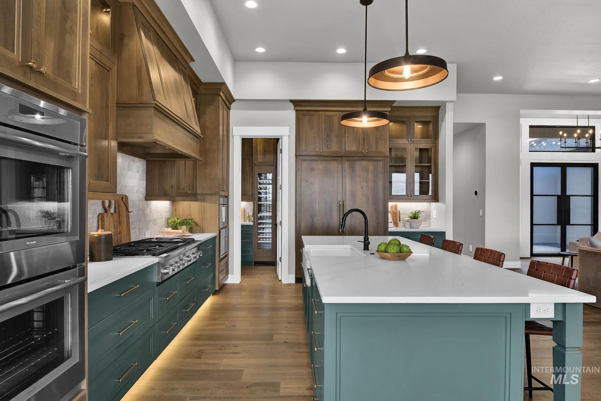 Kitchen with appliances with stainless steel finishes, a kitchen breakfast bar, decorative backsplash, hanging light fixtures, and light wood-style flooring