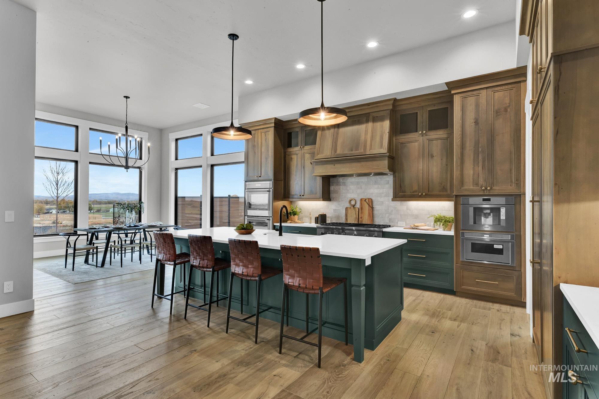 Kitchen with green cabinets, glass insert cabinets, a kitchen island with sink, tasteful backsplash, and a breakfast bar area