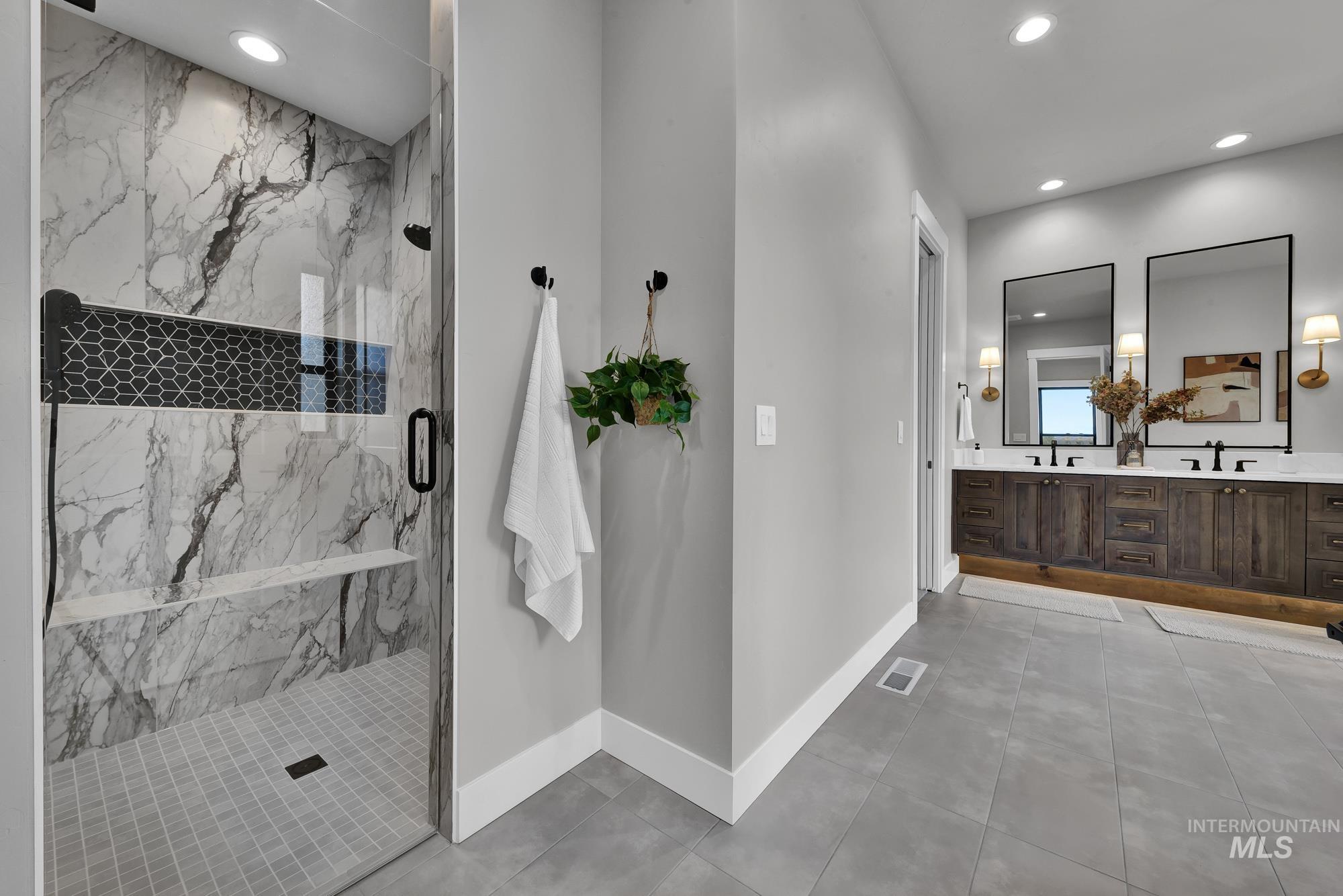 Full bath featuring double vanity, a marble finish shower, recessed lighting, and light tile patterned flooring
