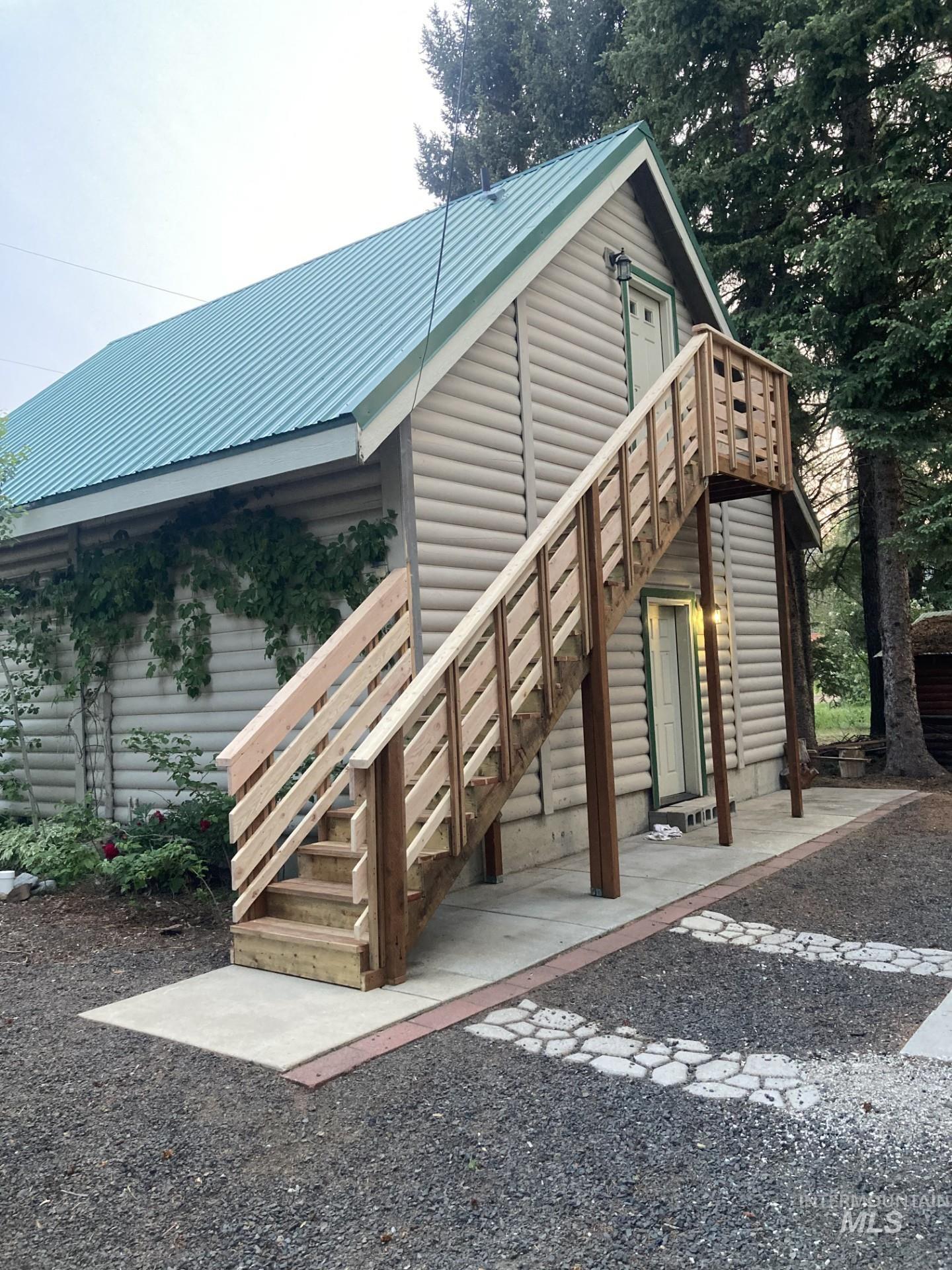 View of side of property with faux log siding, a metal roof, and stairway