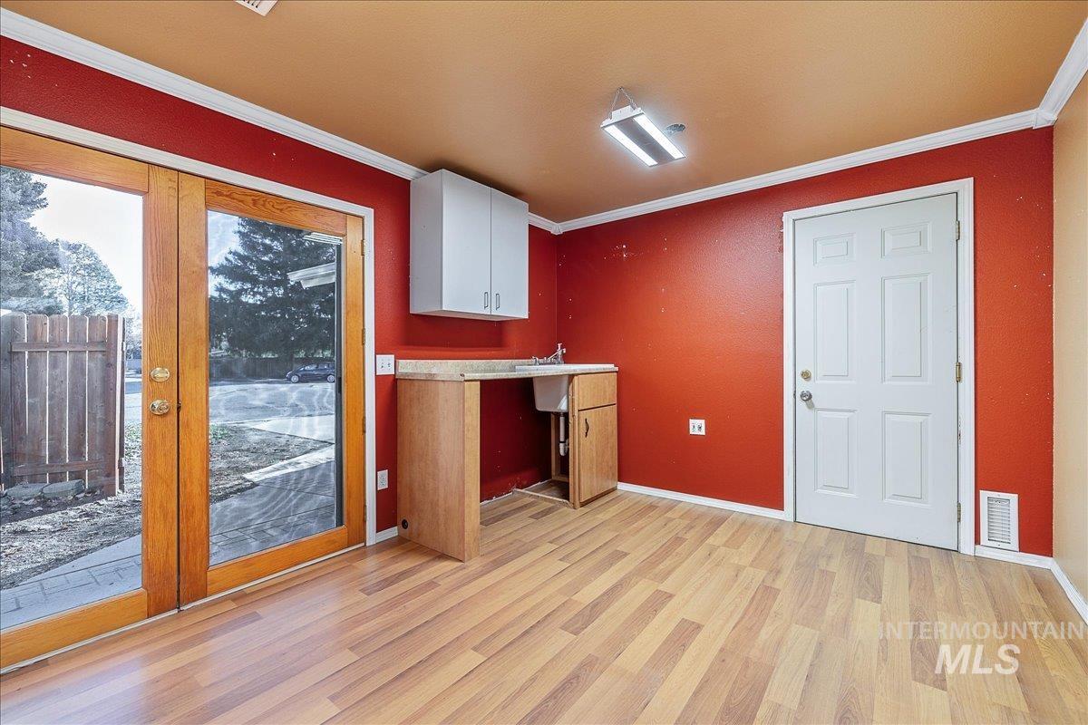 Kitchen featuring crown molding, white cabinets, light wood-type flooring, and light countertops