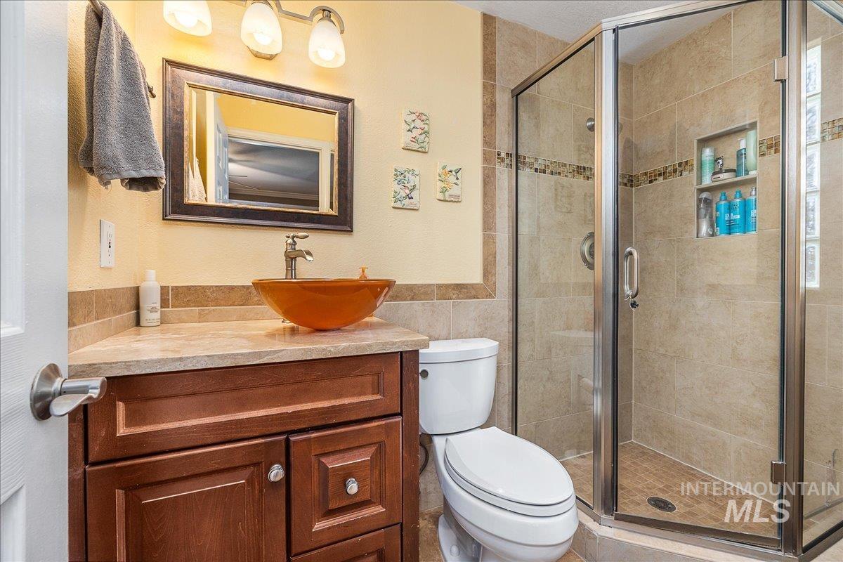 Full bathroom featuring vanity, a shower stall, tile walls, and a wainscoted wall