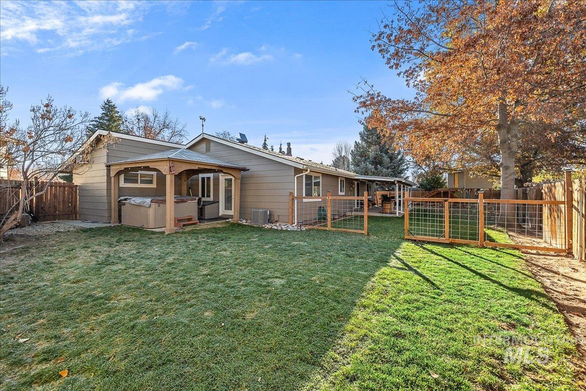 Rear view of house featuring a hot tub, a fenced backyard, and a gate