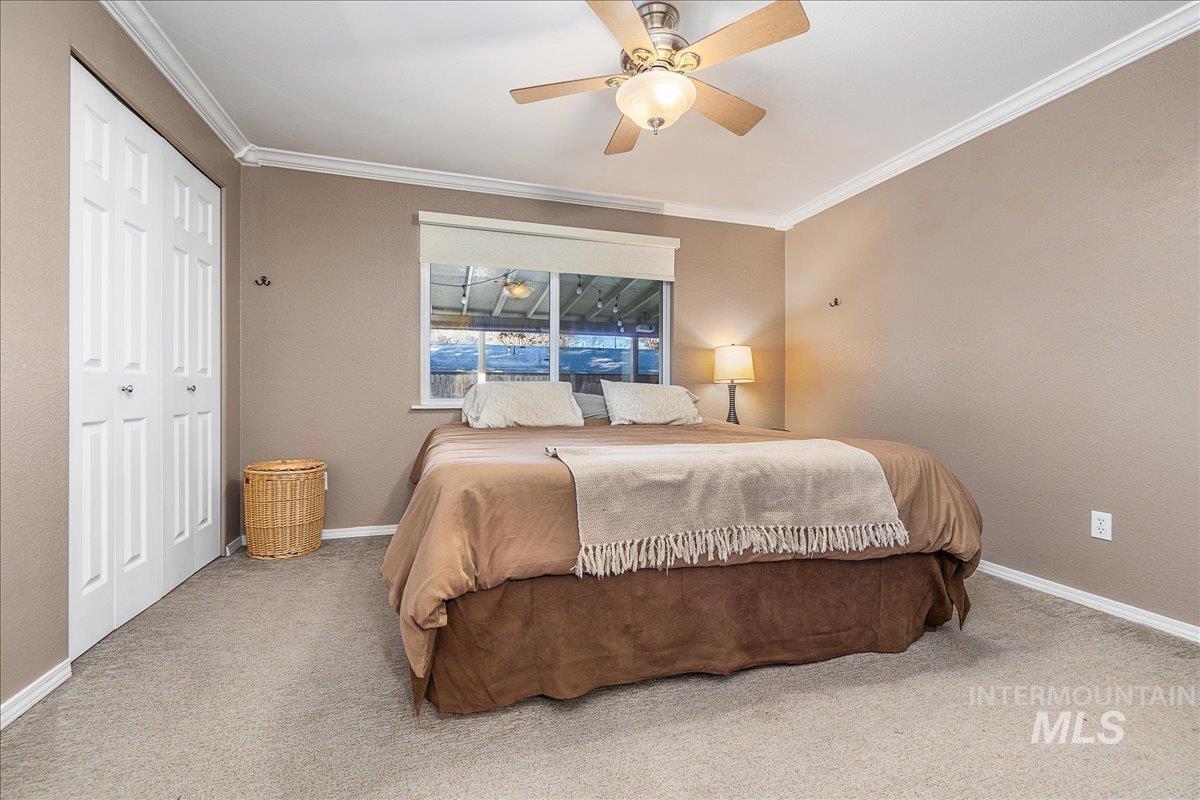 Bedroom with a ceiling fan, ornamental molding, carpet, a closet, and a textured wall