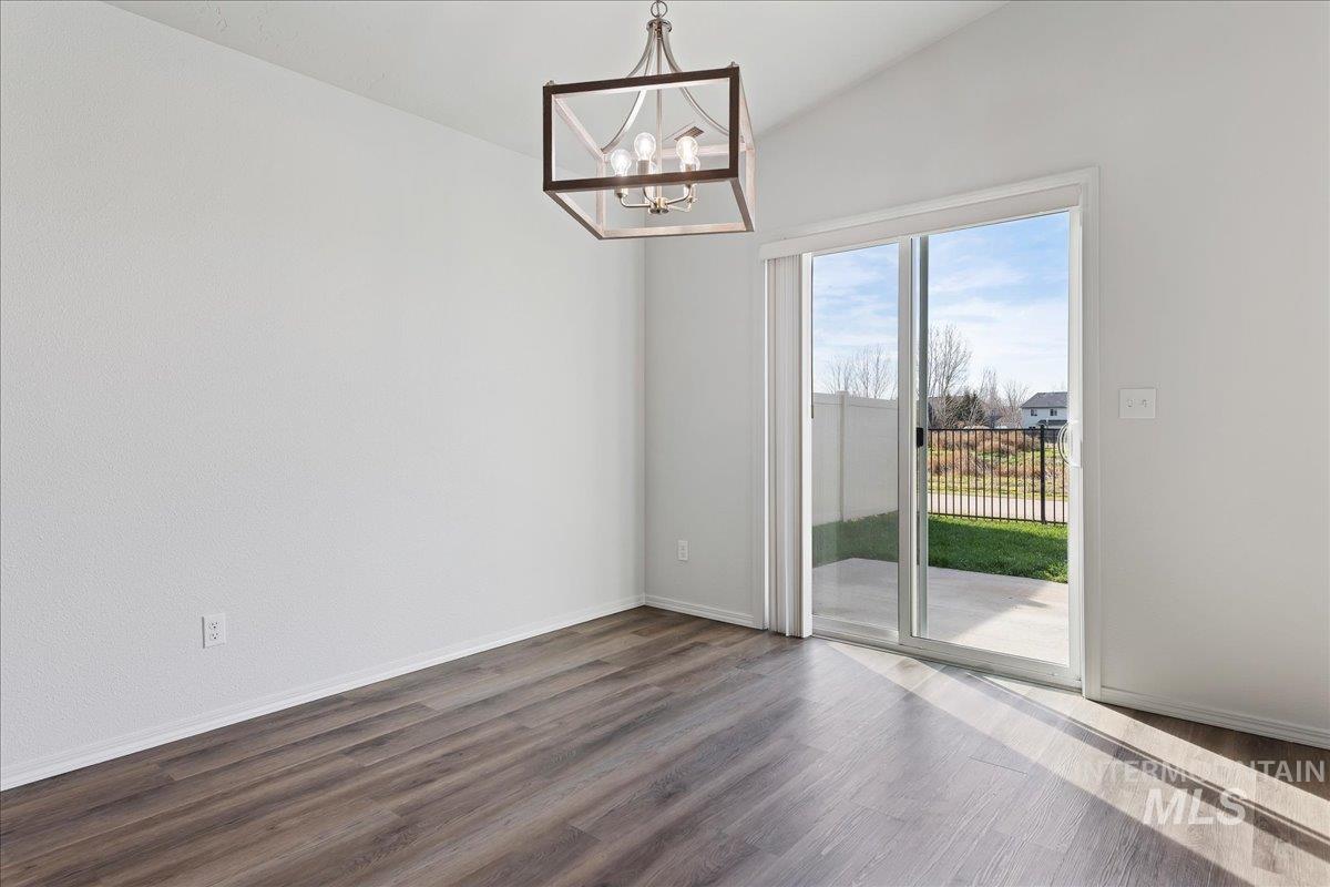 Unfurnished room with vaulted ceiling, dark wood-type flooring, and a chandelier