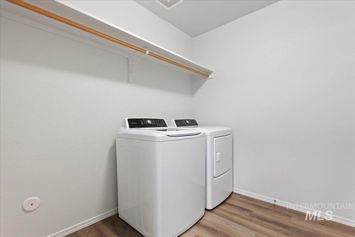 Laundry area with dark wood-style flooring, washer and dryer, and a textured wall