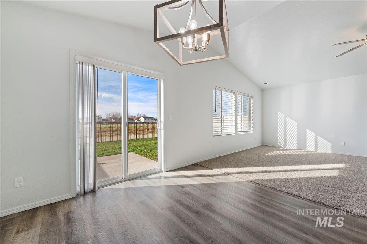 Unfurnished room featuring lofted ceiling, wood finished floors, a chandelier, and ceiling fan