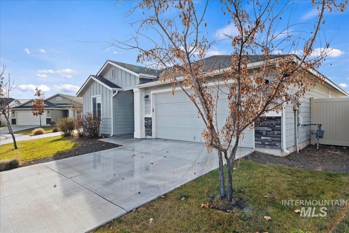 View of front facade featuring board and batten siding, concrete driveway, an attached garage, and a front lawn
