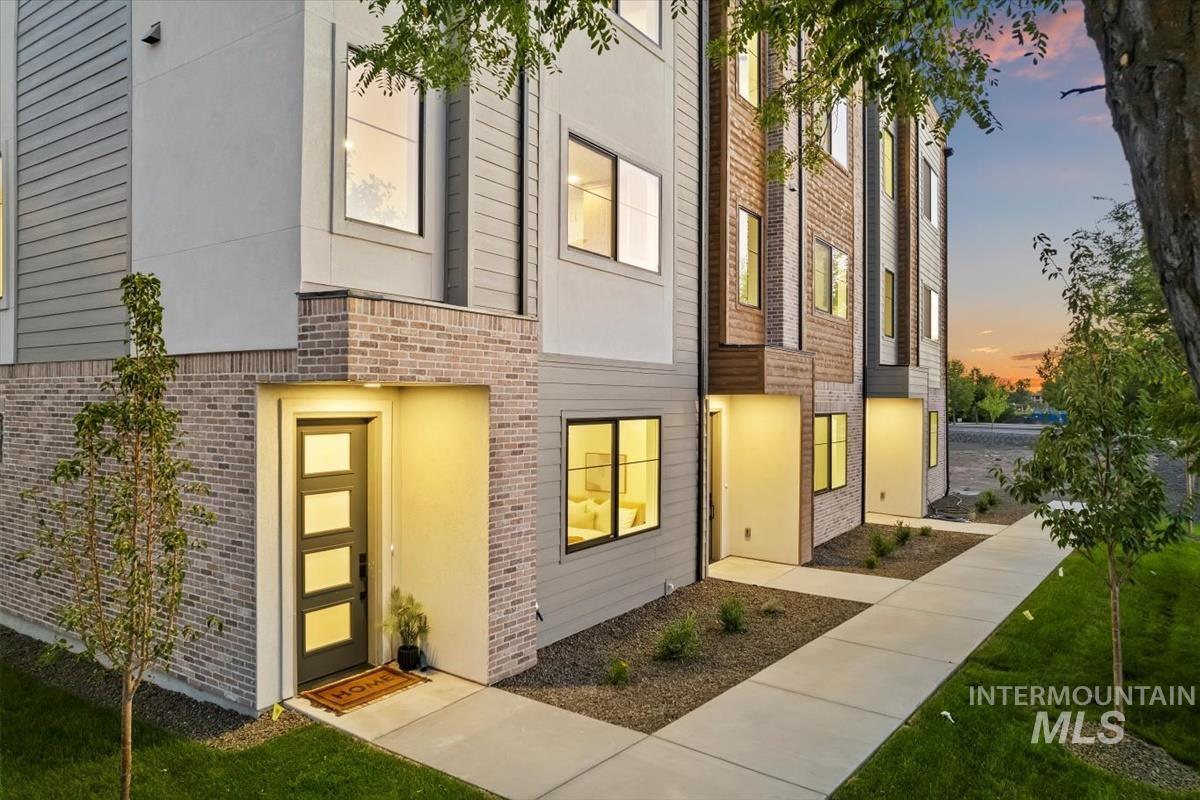 Exterior entry at dusk with brick siding and a lawn