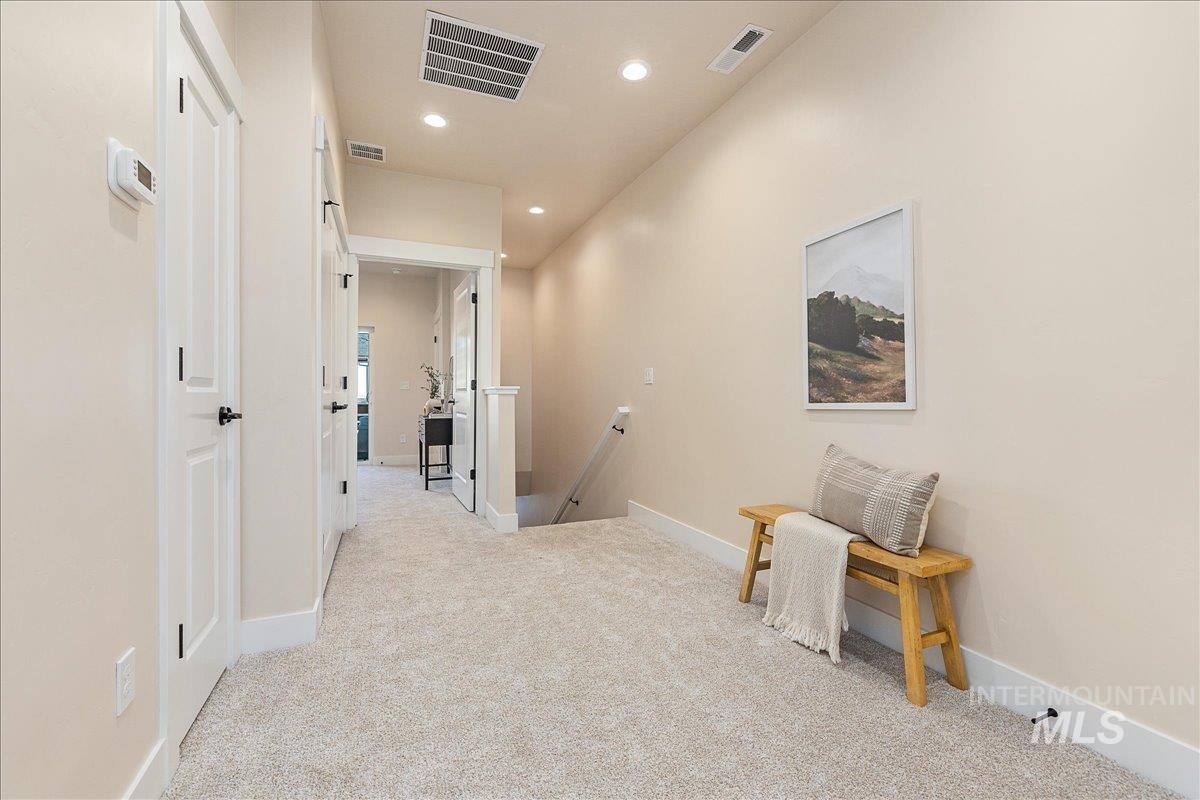 Corridor with an upstairs landing, light carpet, and recessed lighting