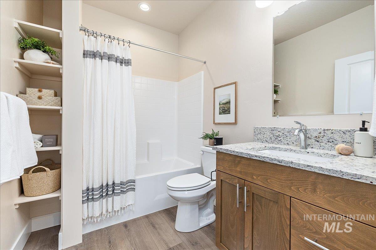 Full bathroom featuring light wood-type flooring, vanity, and shower / tub combo